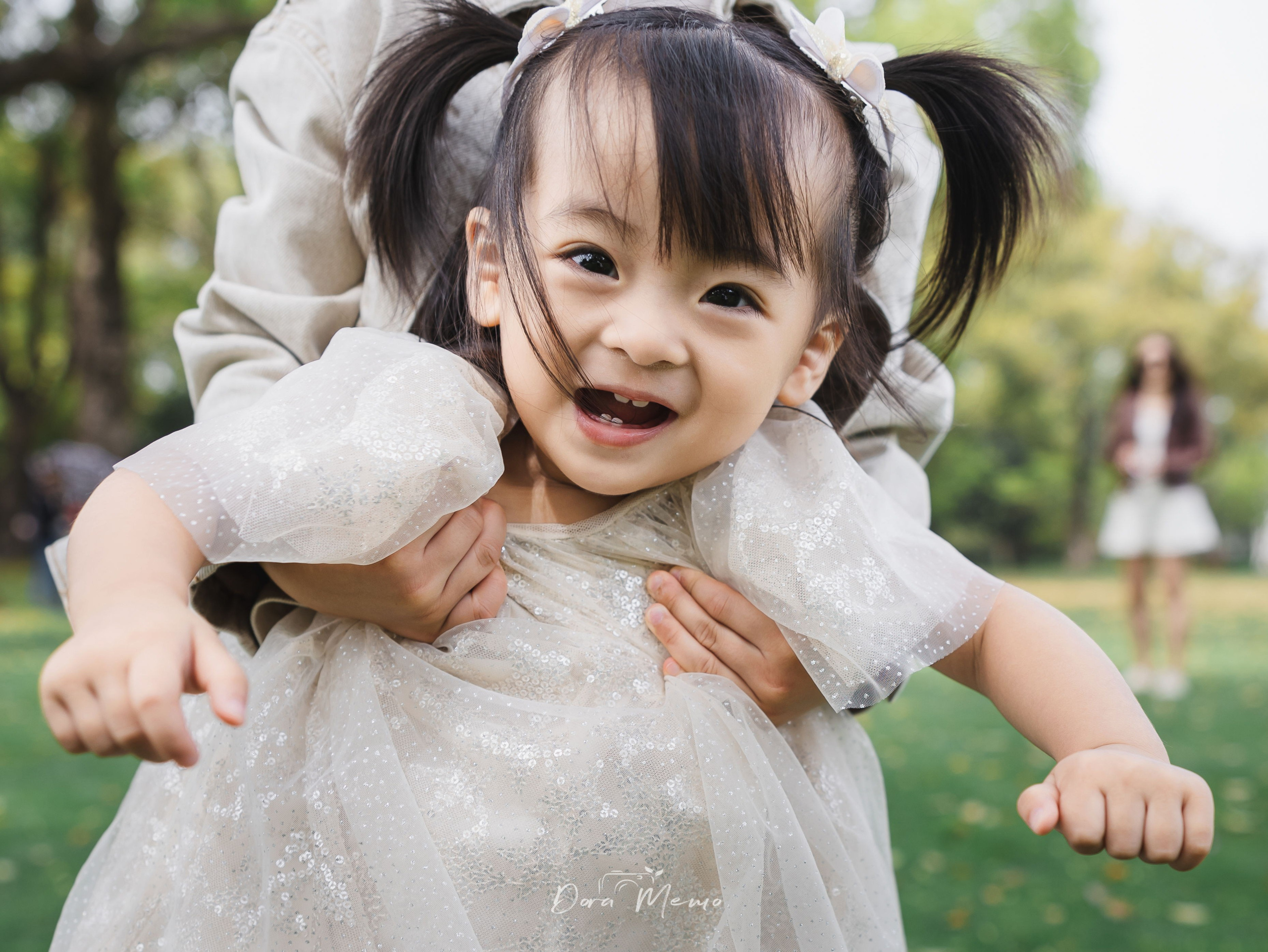 Close-up of a toddler girl smiling, a tiny bow in her hair