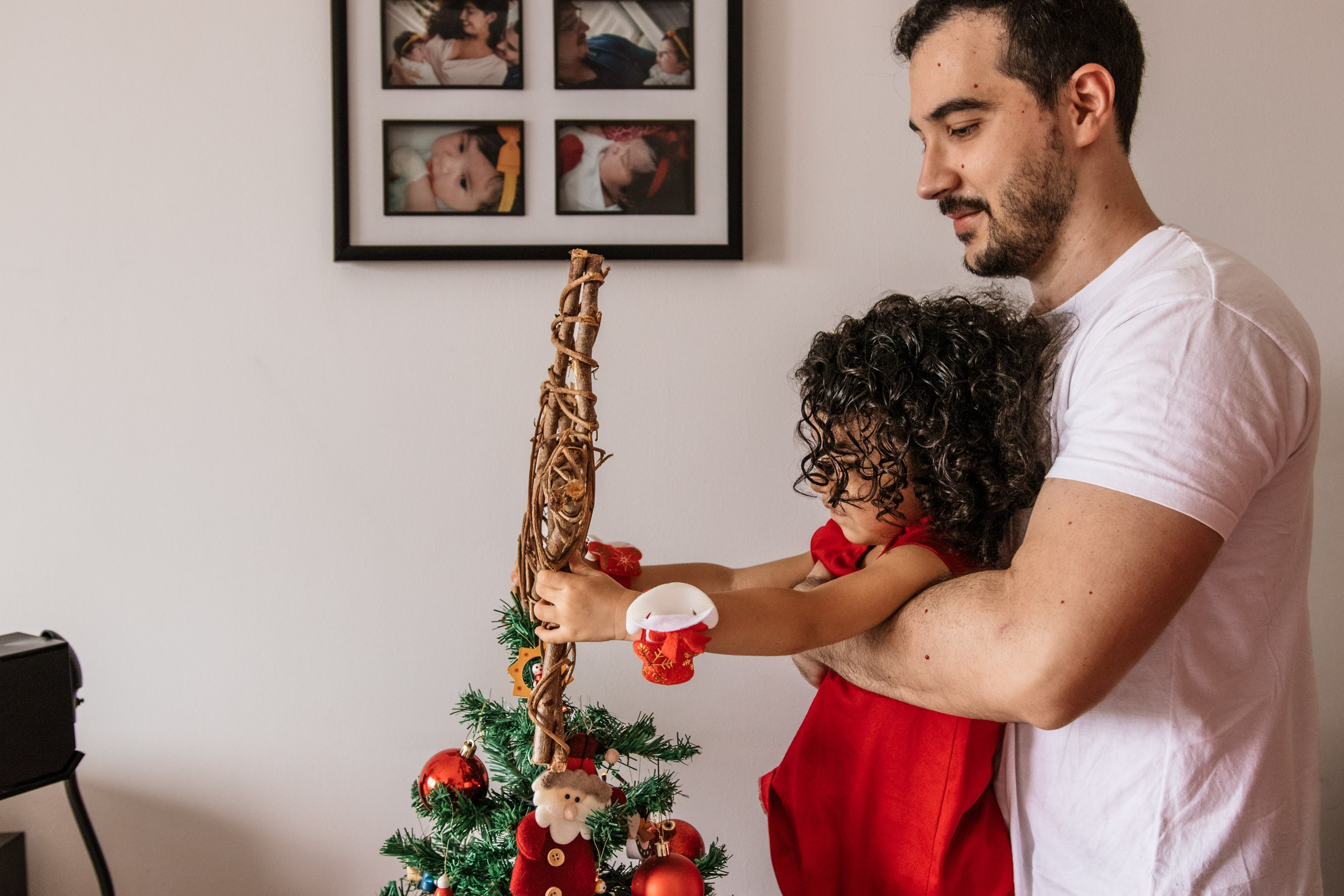criança coloca estrela em árvore de natal