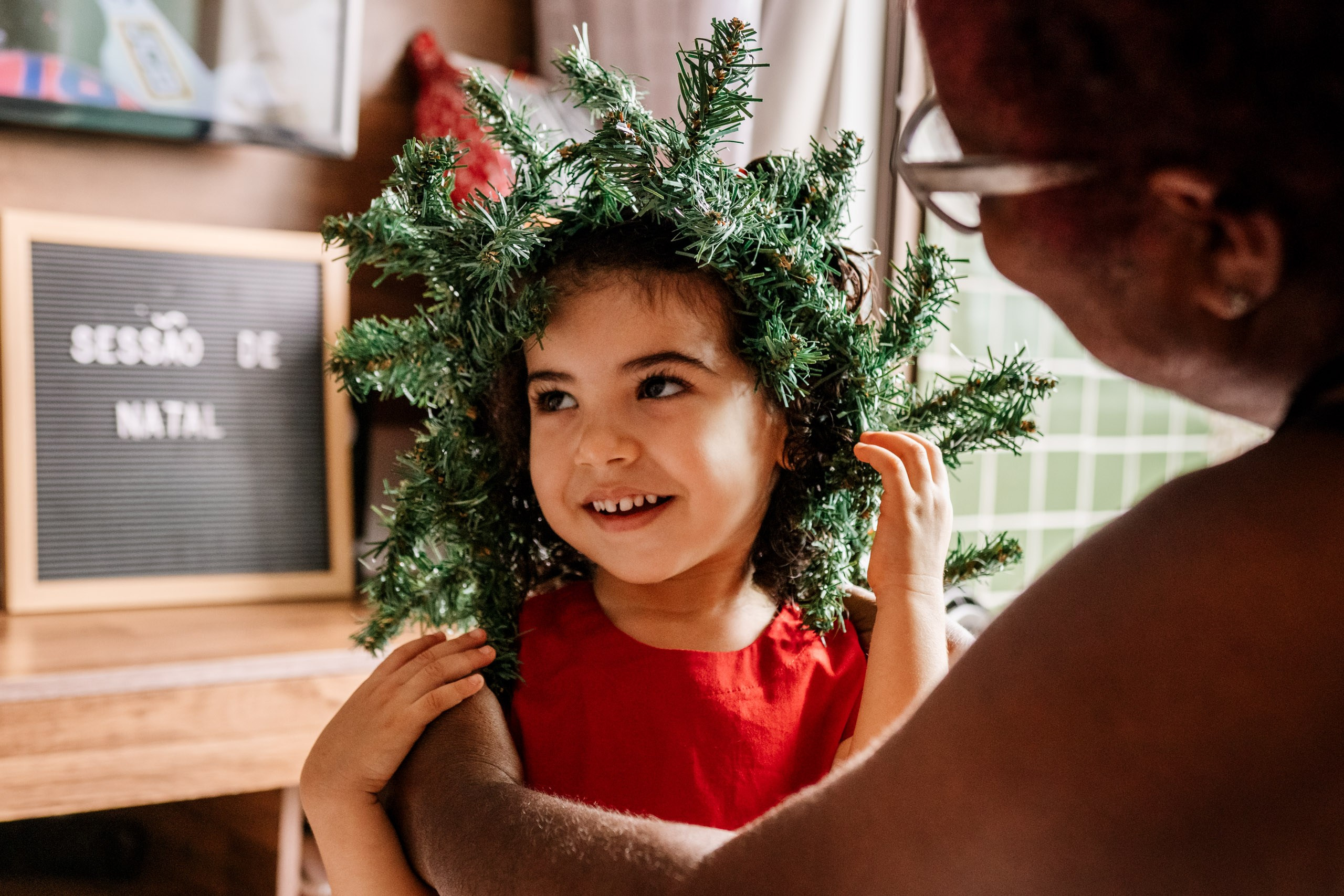 menina brinca em montagem de árvore de natal