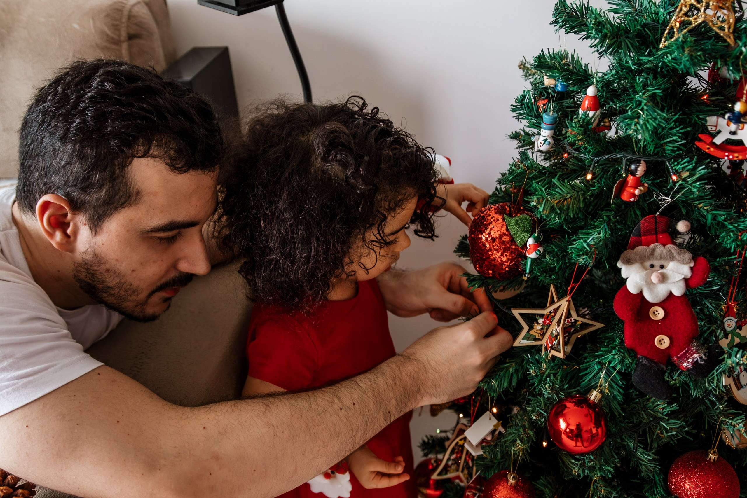 pai e menina colocando enfeite em árvore de natal