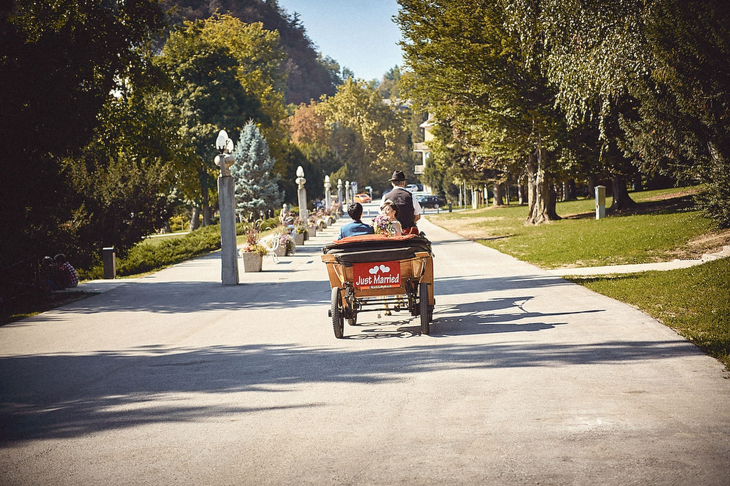 A young Japanese couple riding in the back of a carriage is seen from a distance as they enjoy a horse and carriage ride in Bled, Slovenia.