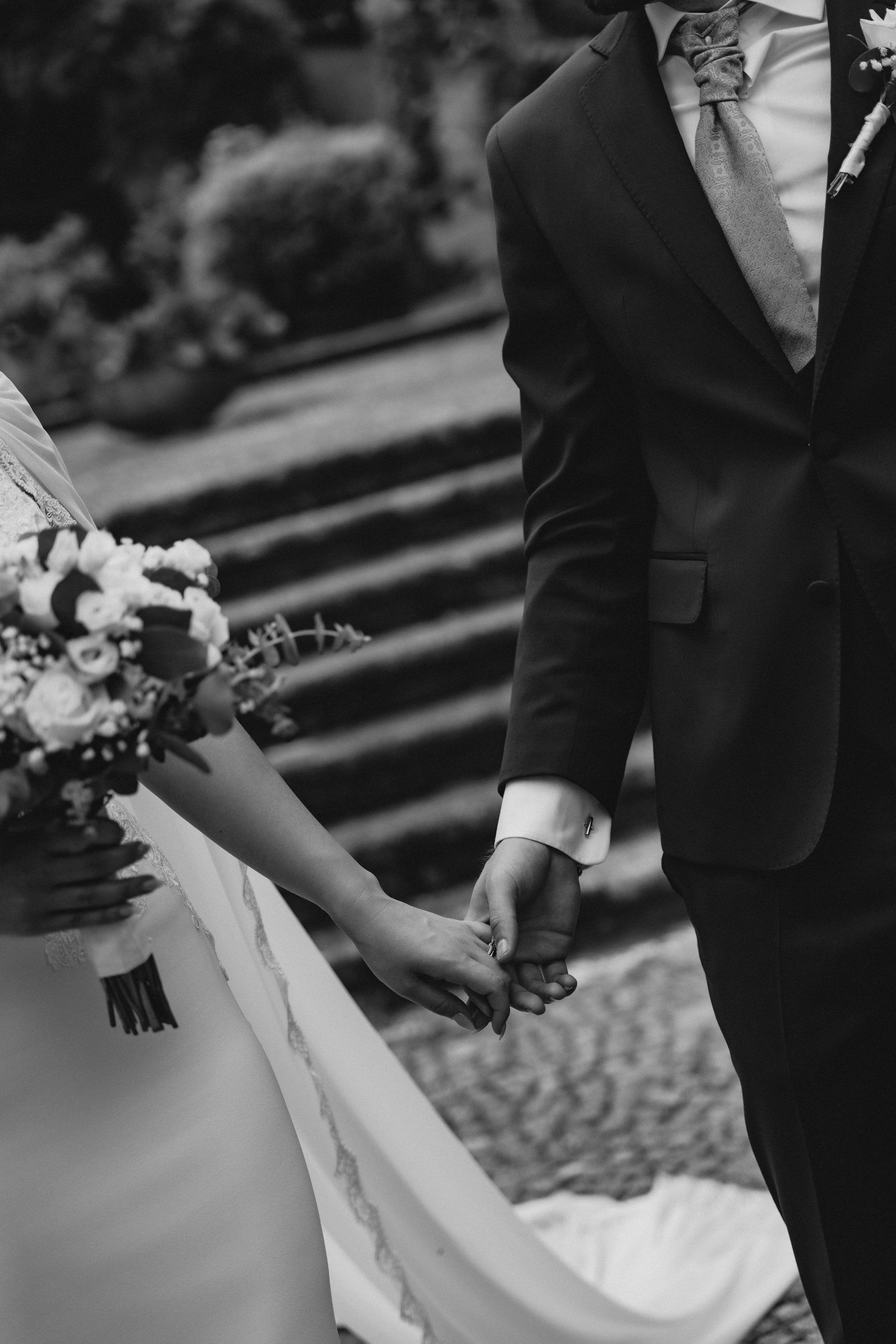 Detalhe editorial de mãos entrelaçadas no dia do casamento, símbolo de amor e proximidade