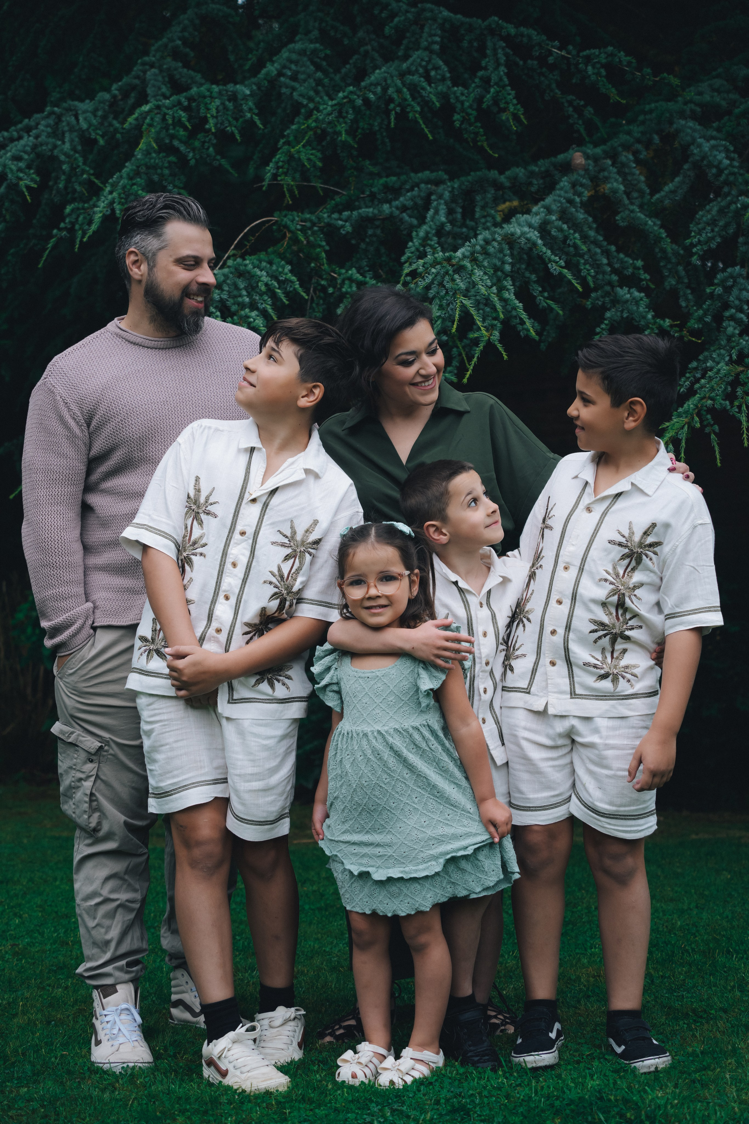 Family portrait in matching white outfits at garden, timeless family photography.