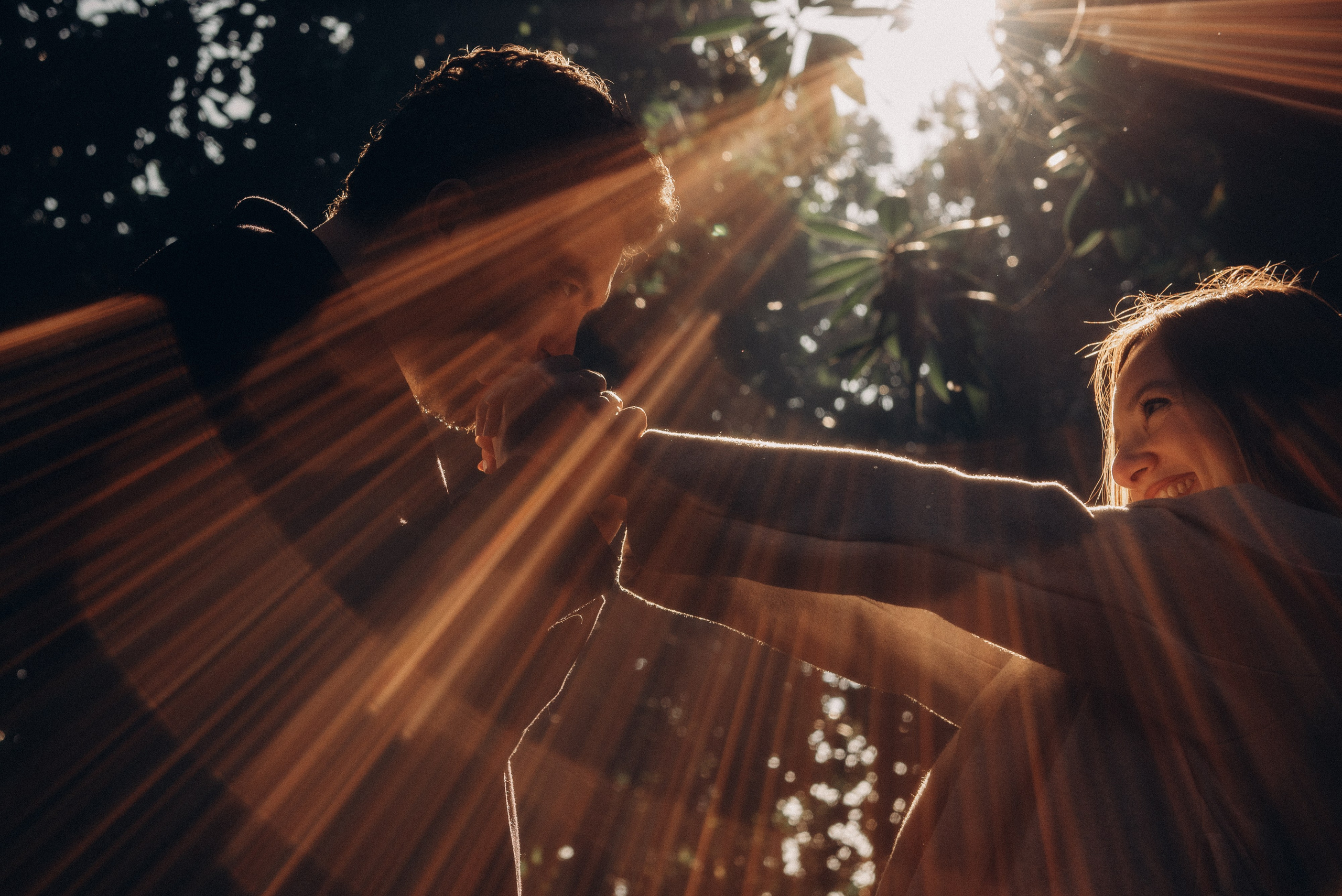 Joyful moment of a couple laughing together under autumn trees in Milan's park. Engagement photoshoot Milan