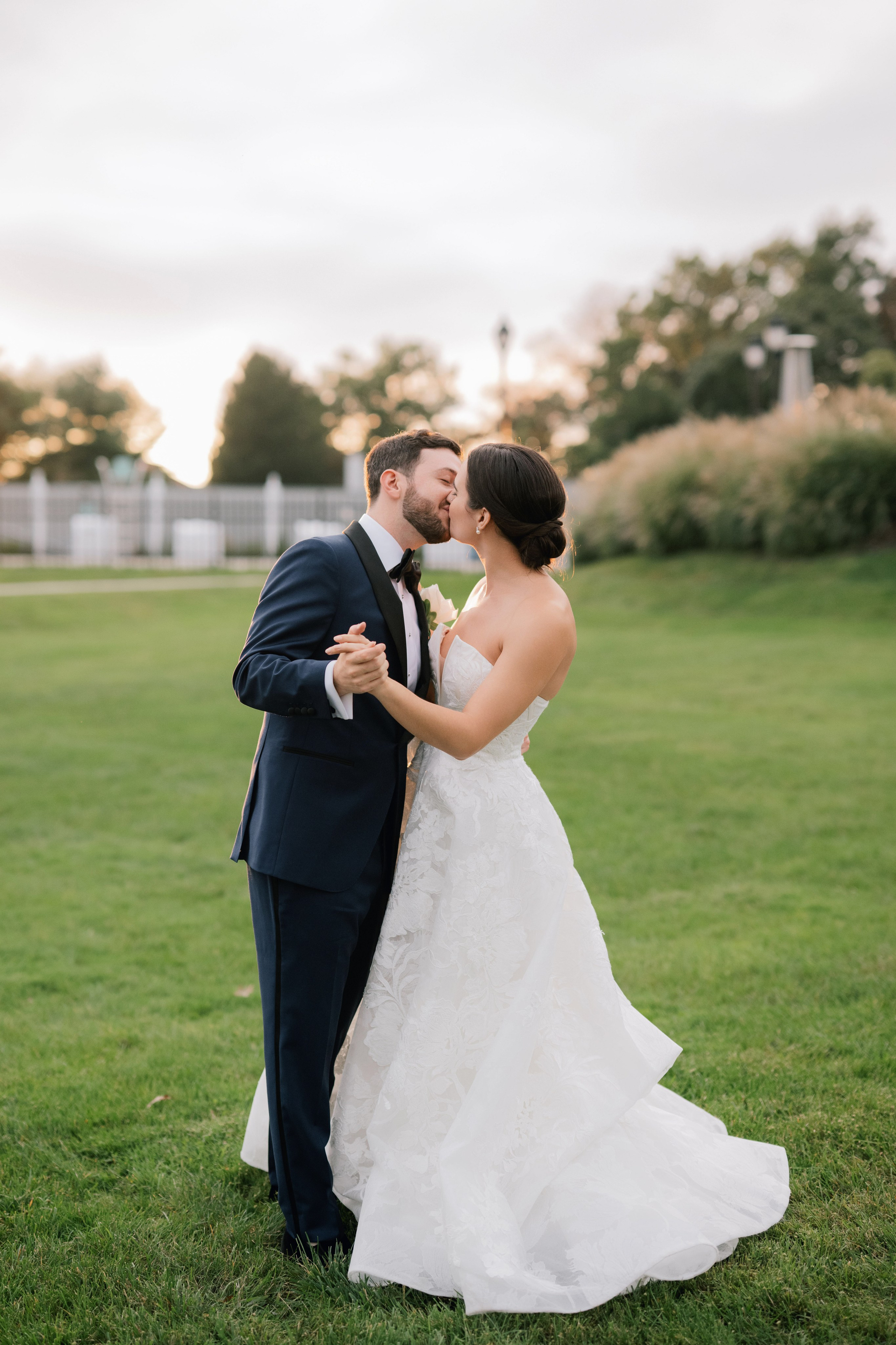 a bride and groom kissing in the grass