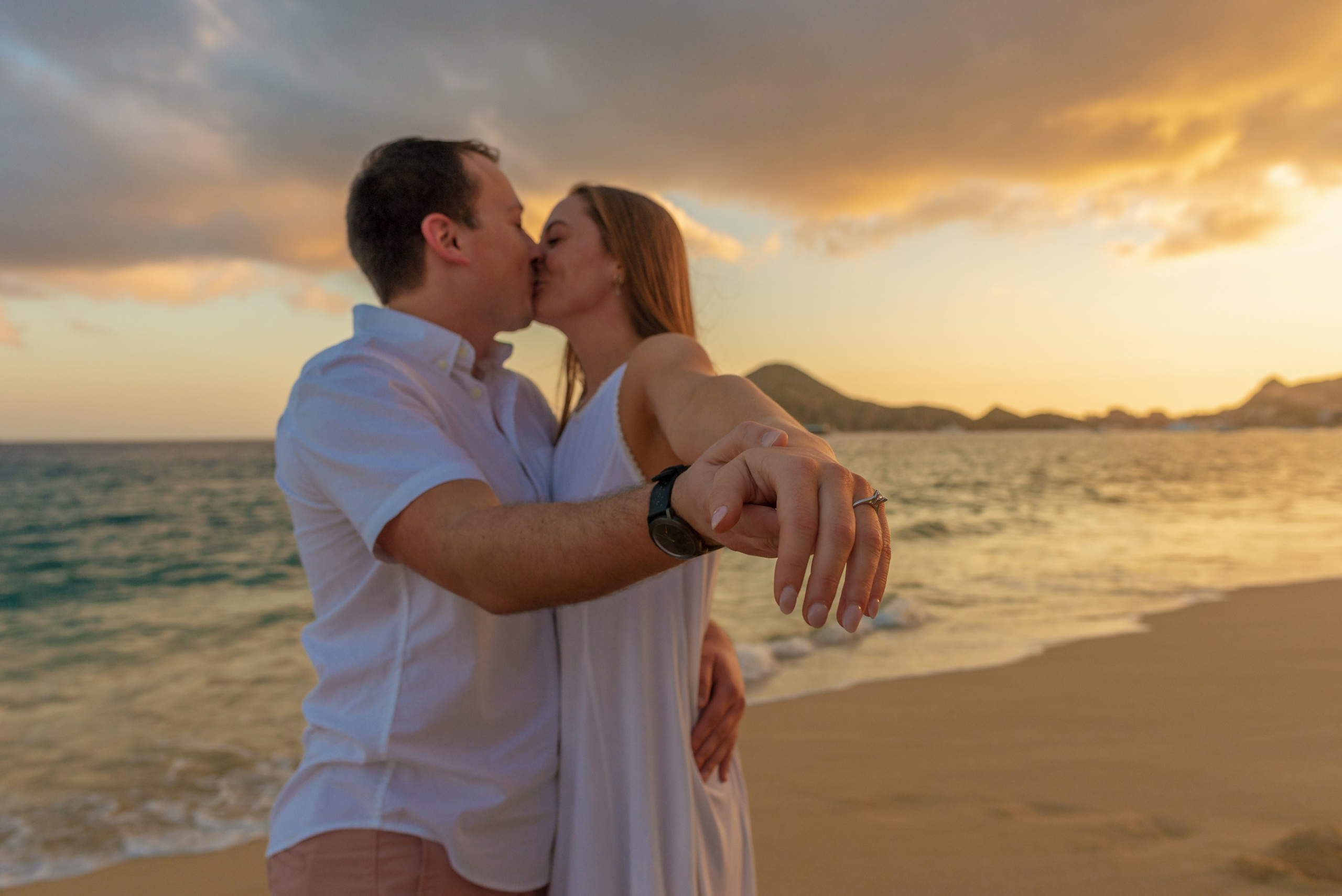 Emotional woman showing engagement ring after surprise proposal Los Cabos beach