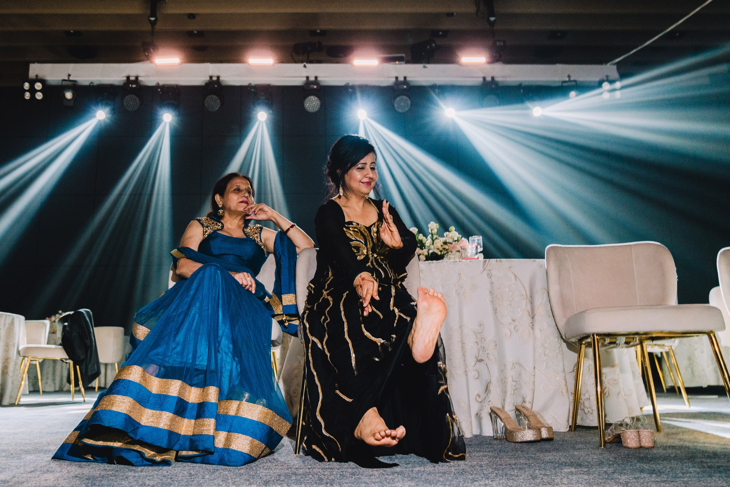Two ladies are seating on a chair and dancing in a funny way