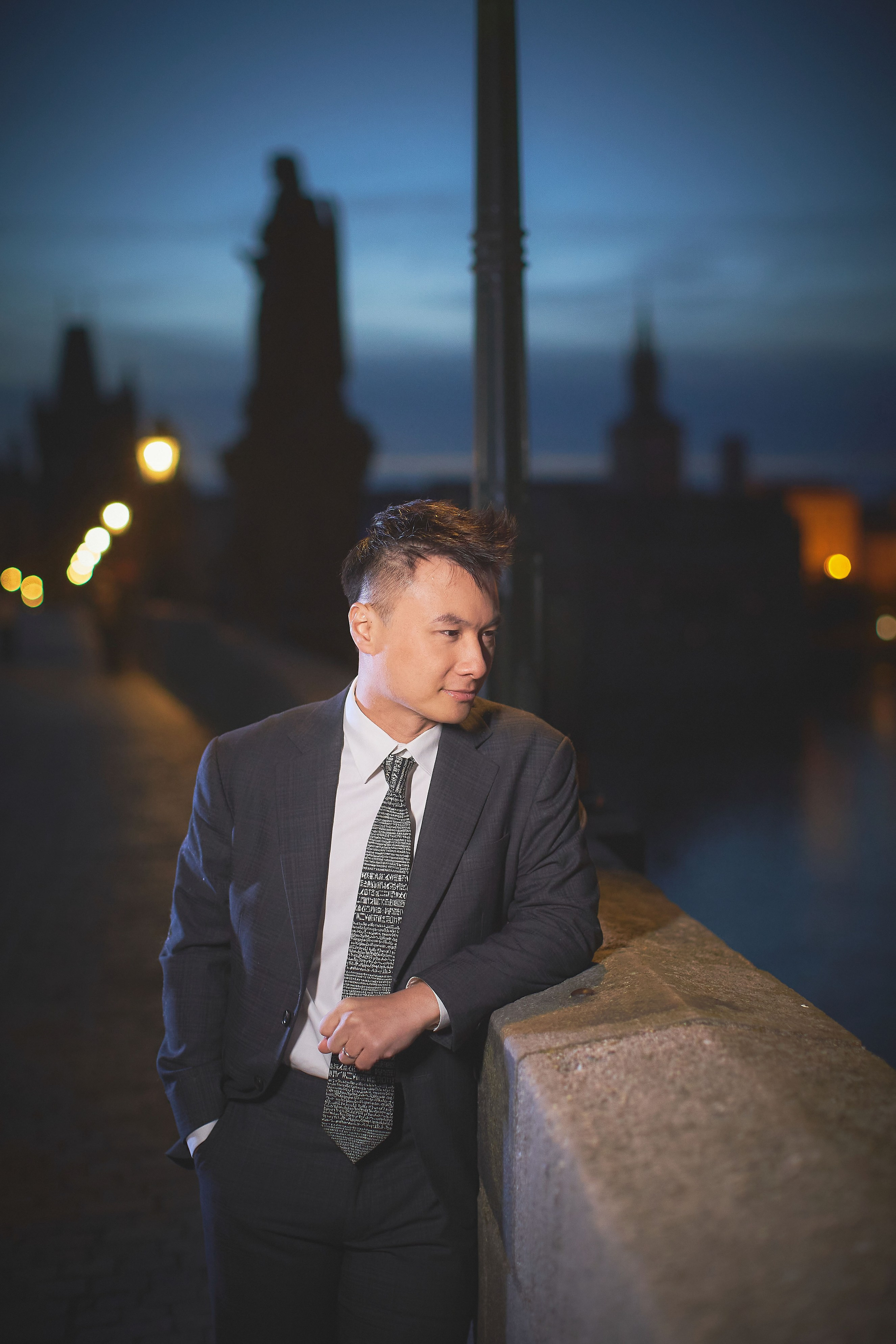 Groom Conan gazing at the view on Charles Bridge while bride Eva’s hair is retouched at dawn.