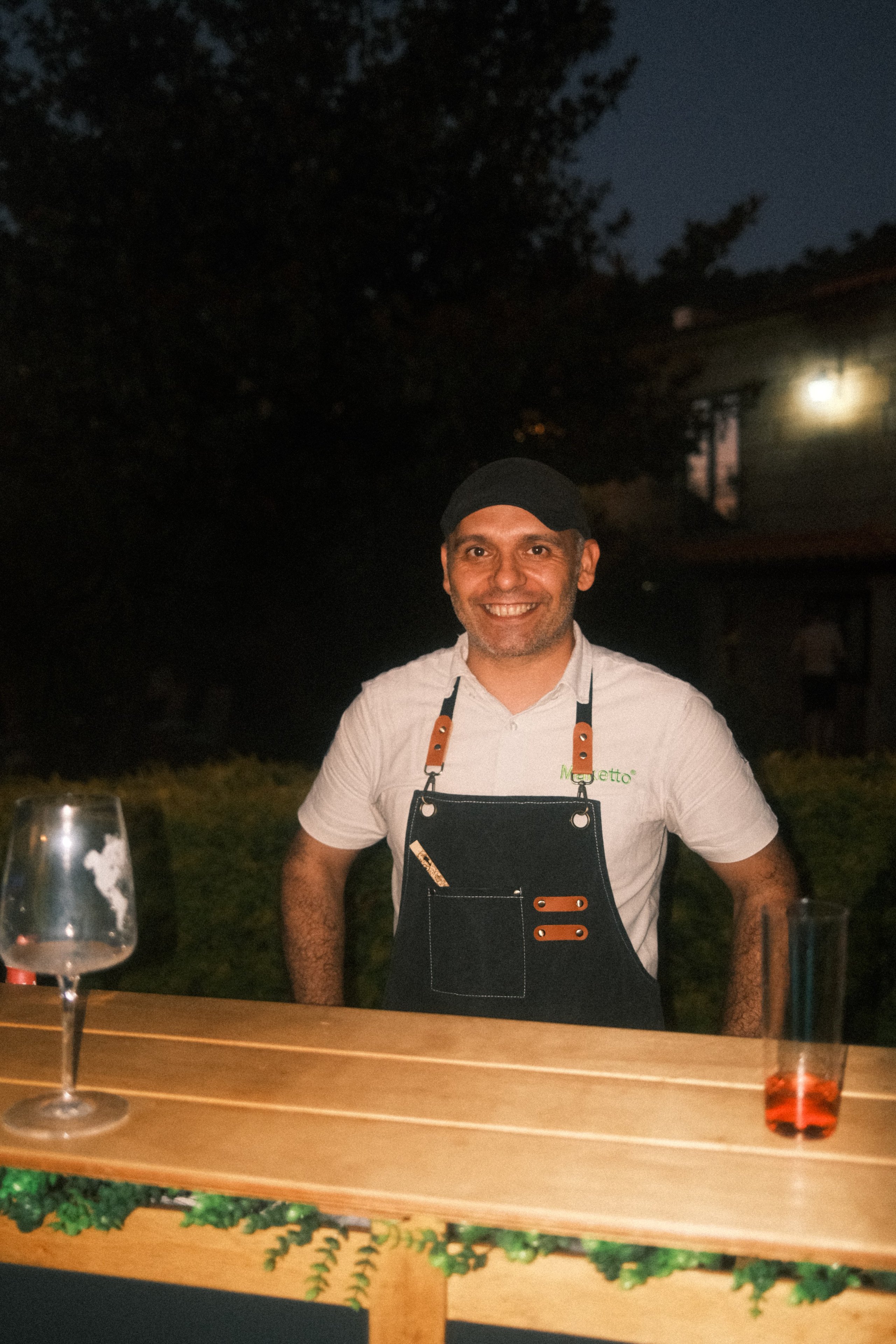 Fotografia de retrato em evento noturno com o bartender a sorrir atrás do balcão de bar iluminado, captada pela Khave Media