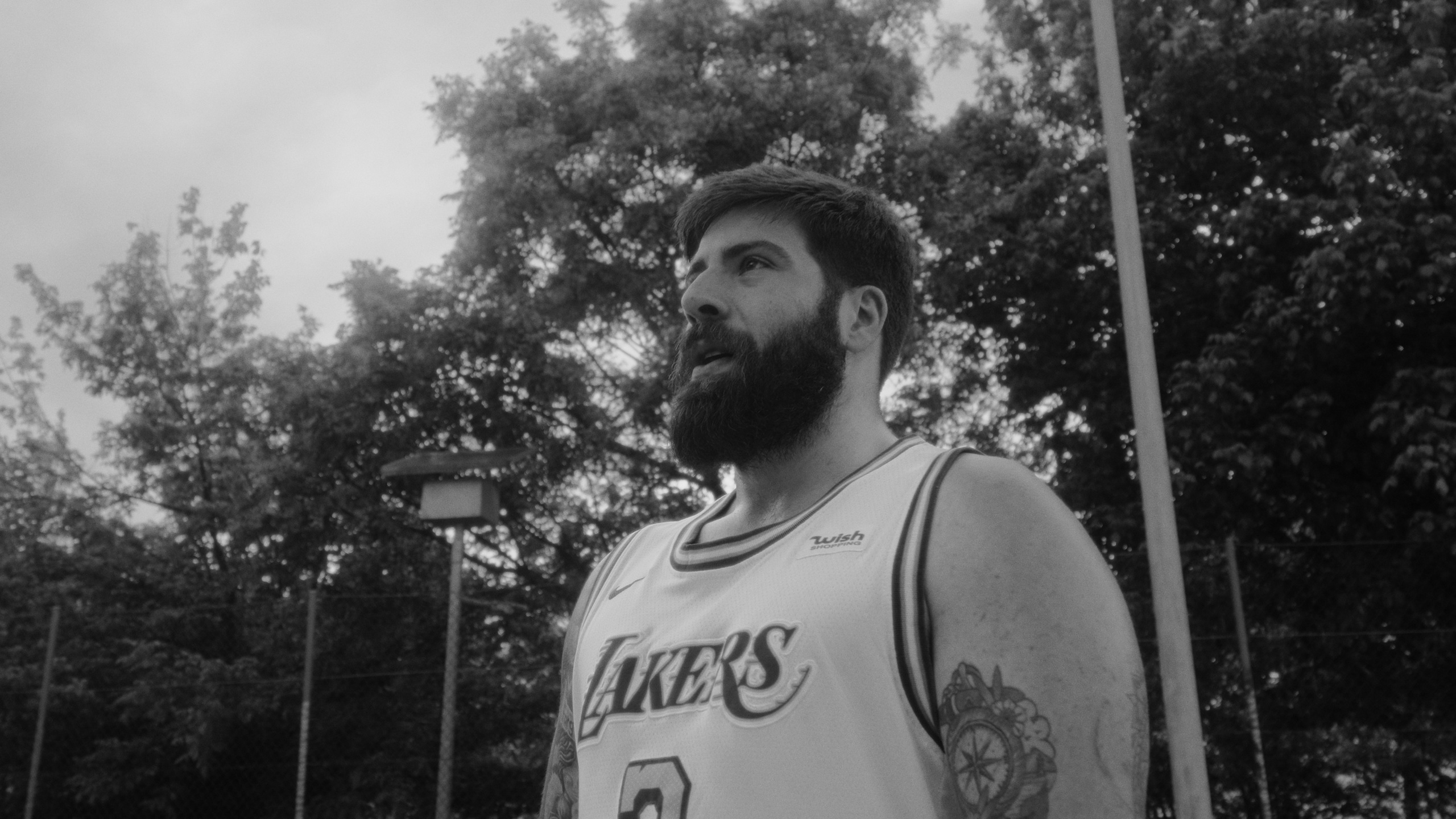 Fotografia de retrato desportivo a preto e branco num ângulo baixo de um jogador de basquetebol com tatuagens, produzida pela Khave Media