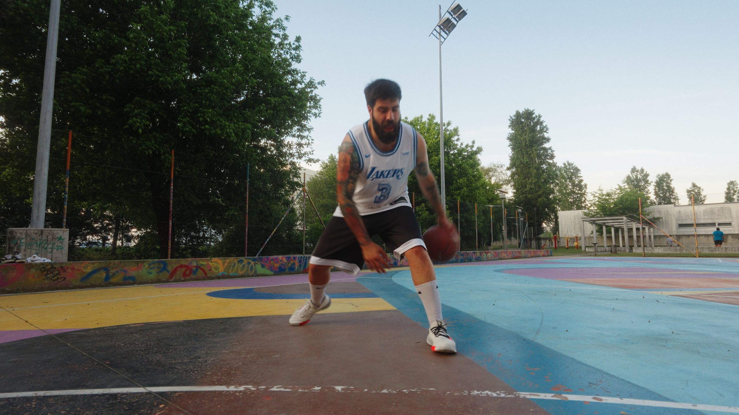 Fotografia desportiva de um jogador de basquetebol a driblar num campo colorido ao ar livre, captada pela Khave Media