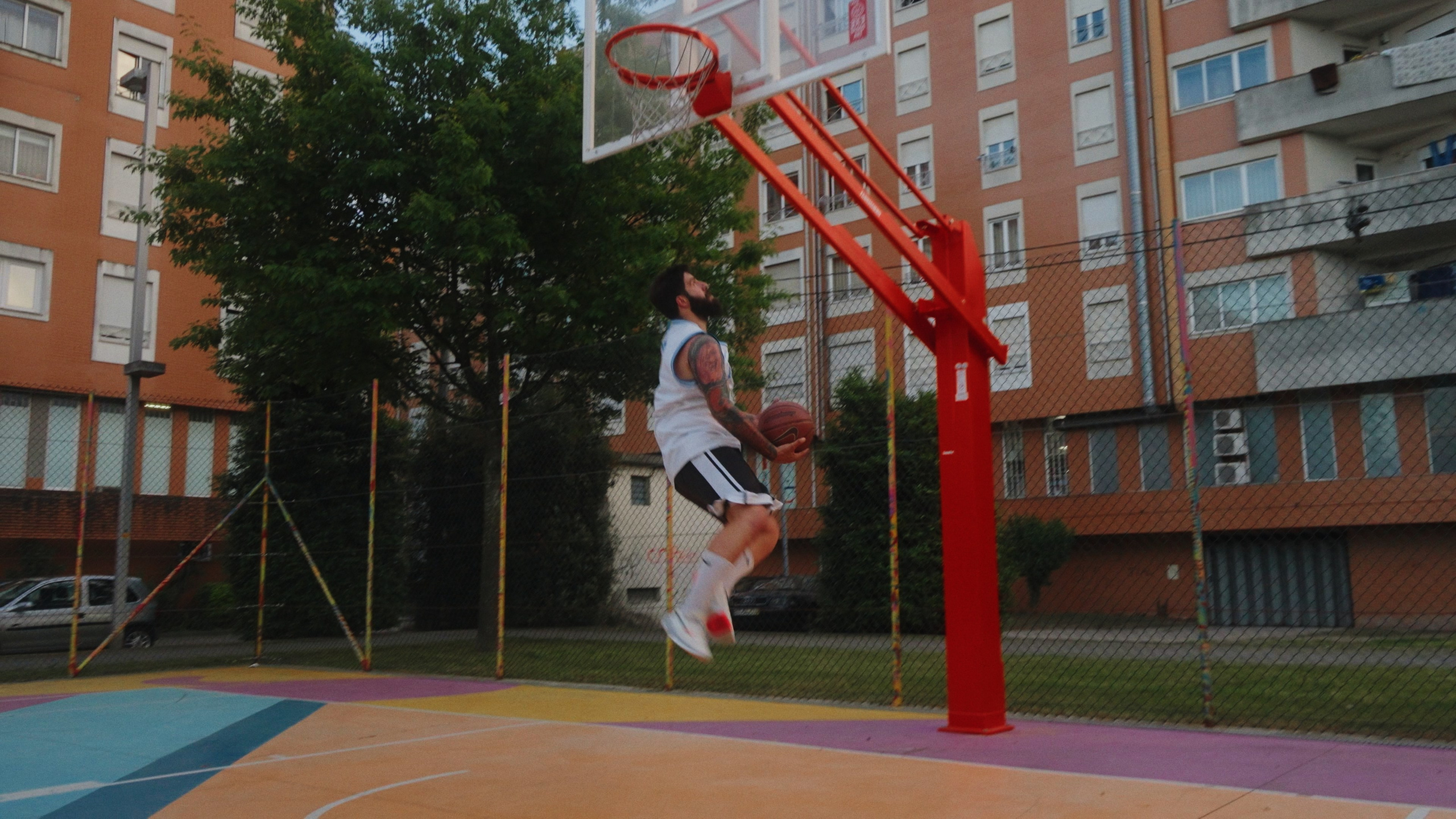 Fotografia desportiva de um jogador de basquetebol no ar junto à tabela num campo urbano no norte de Portugal, captada pela Khave Media