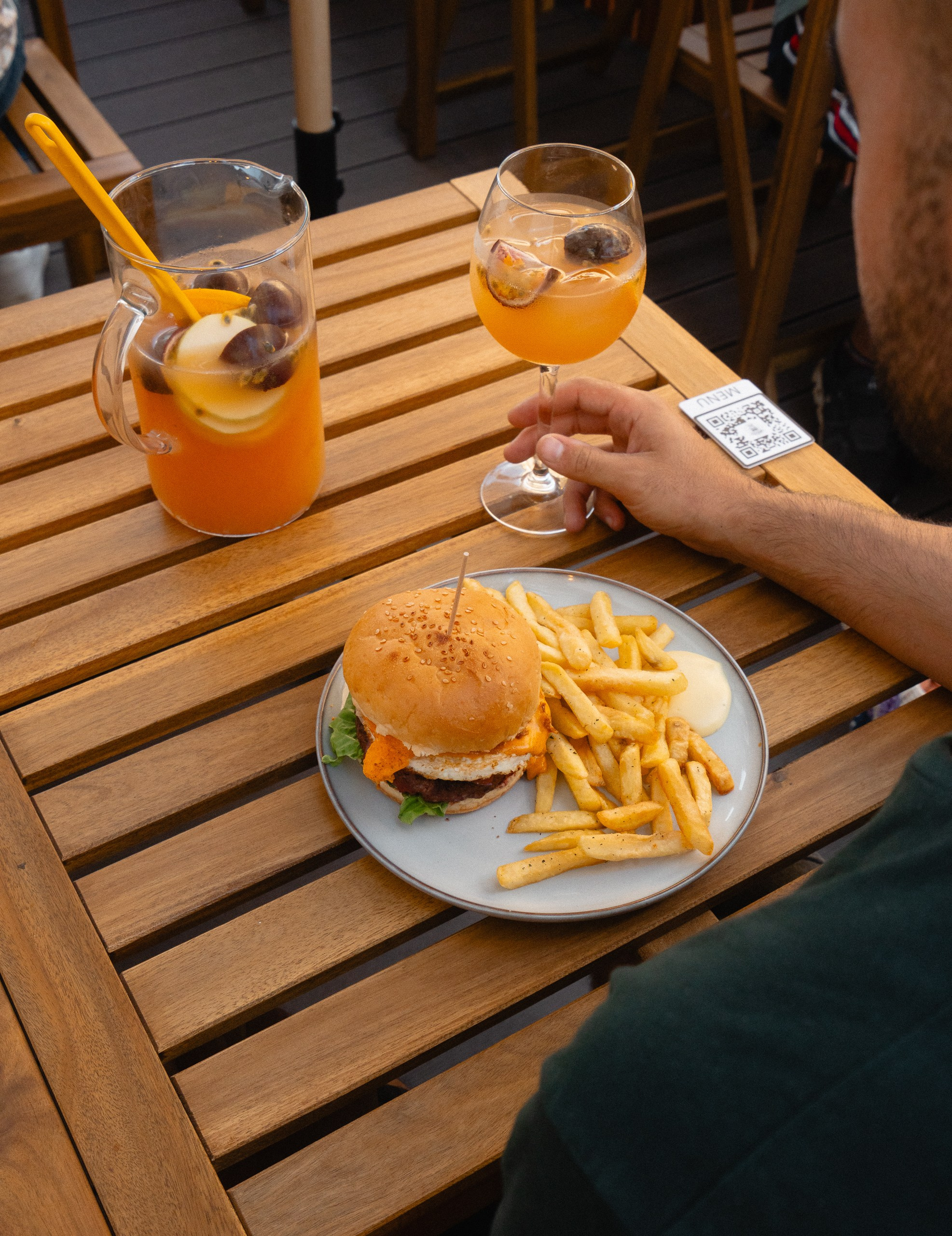 Fotografia lifestyle de restauração com uma refeição de hambúrguer e bebida numa mesa de esplanada ao ar livre, produzida pela Khave Media