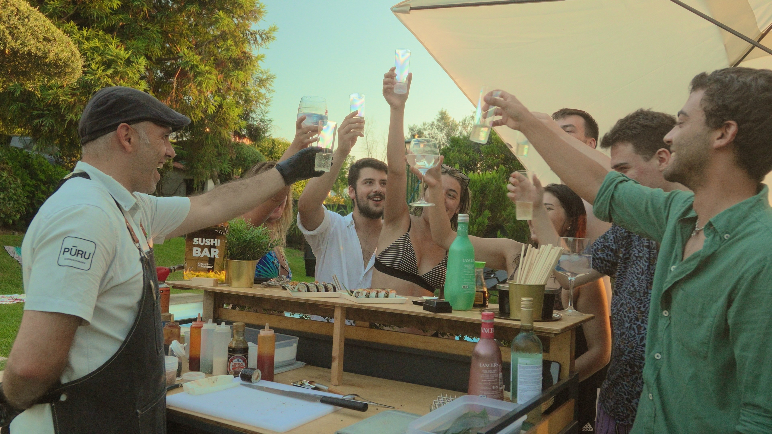 Fotografia de eventos e lifestyle de um grupo de convidados a celebrar junto a um bar ao ar livre num jardim, captada pela Khave Media