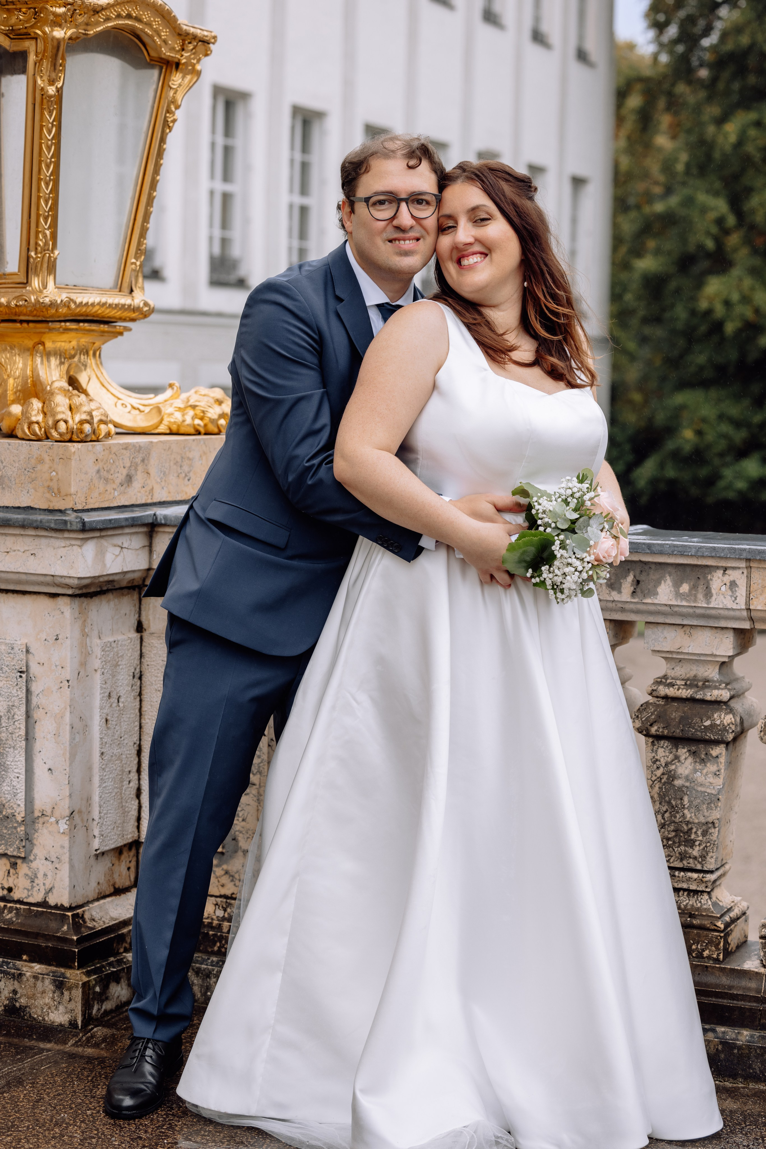 Bräutigam umarmt die Braut vor dem Schloss Nymphenburg