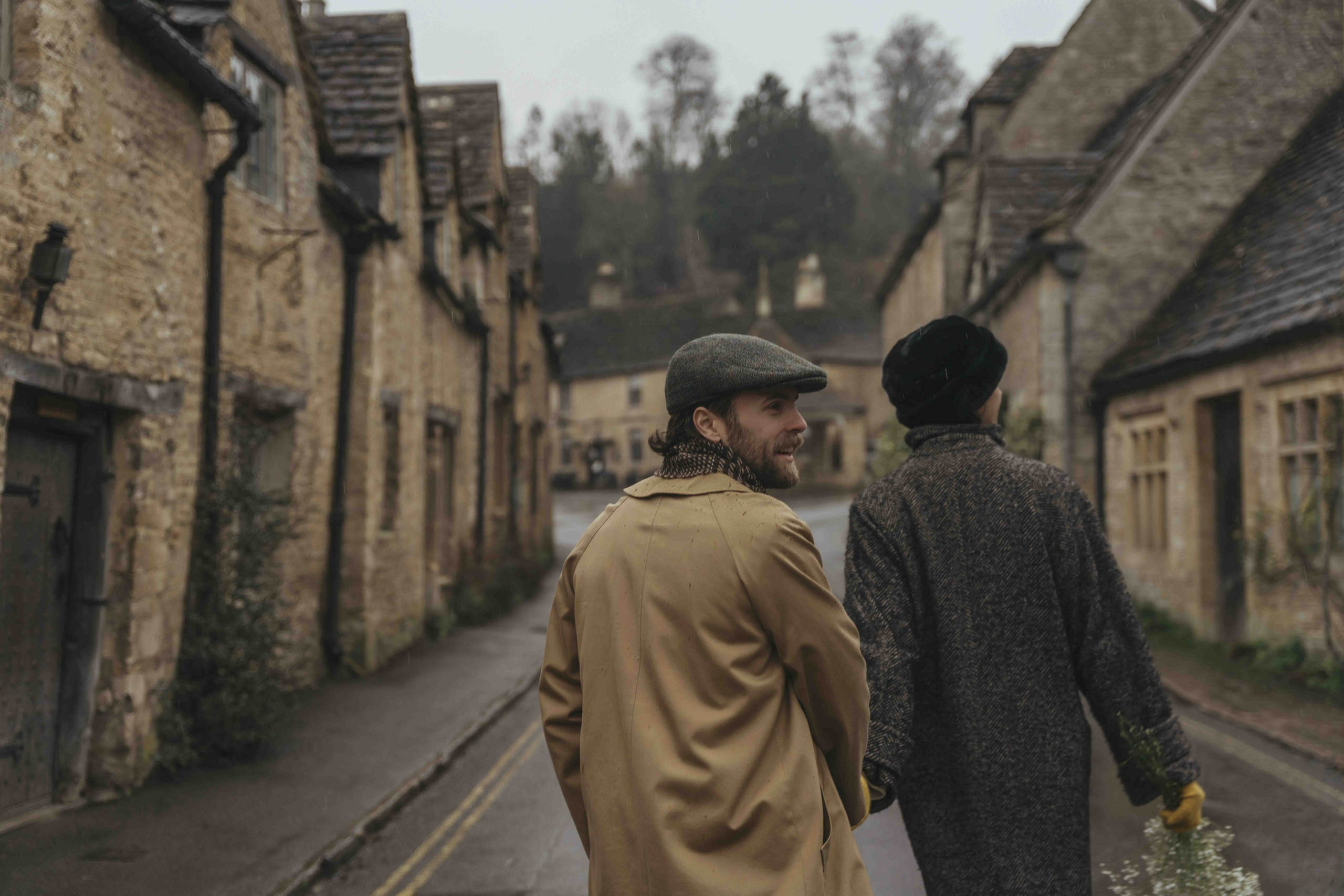 historic street in Castle Combe Cotswolds with wet road and cinematic rainy mood