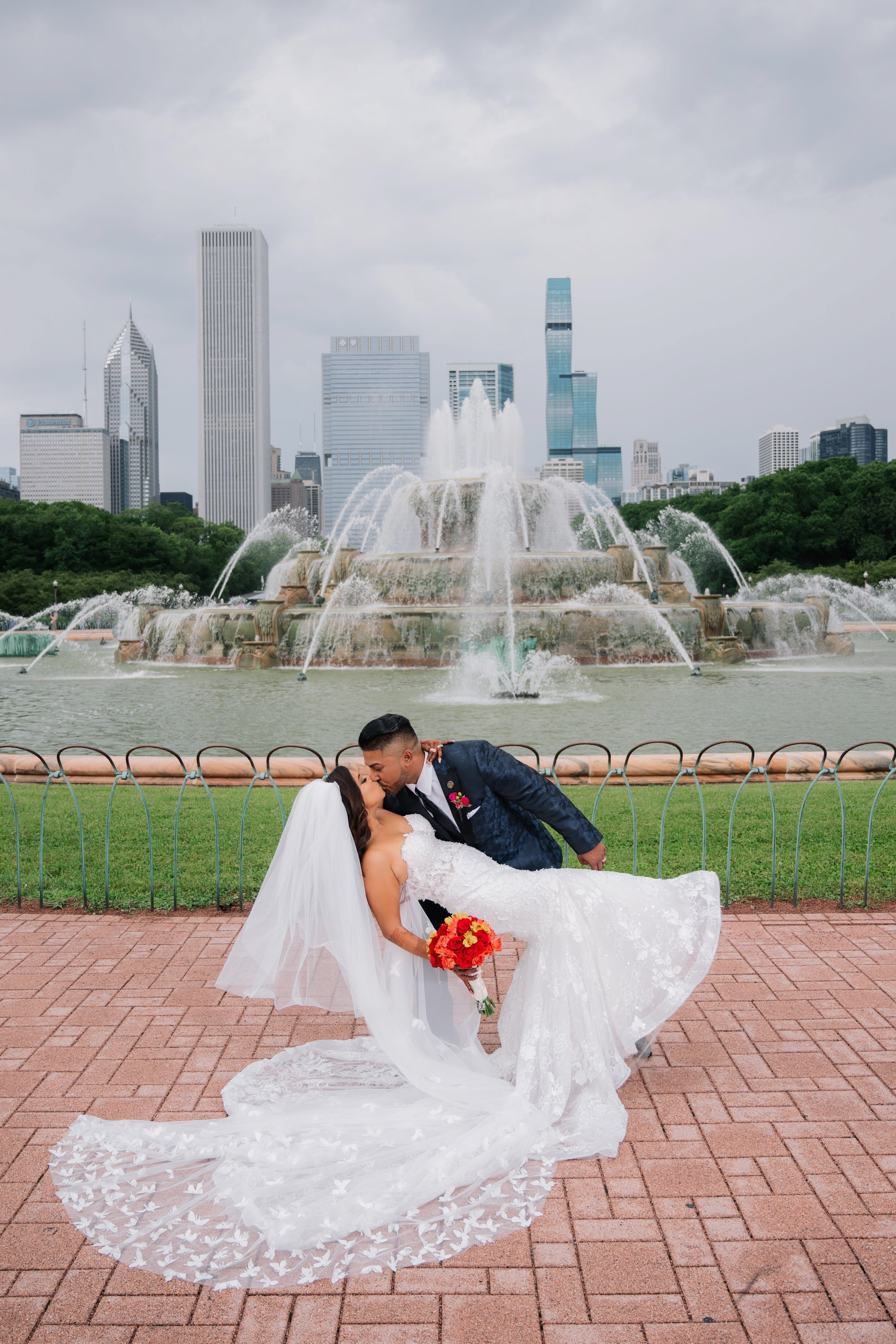 a bride and groom kissing in front of a fountain
