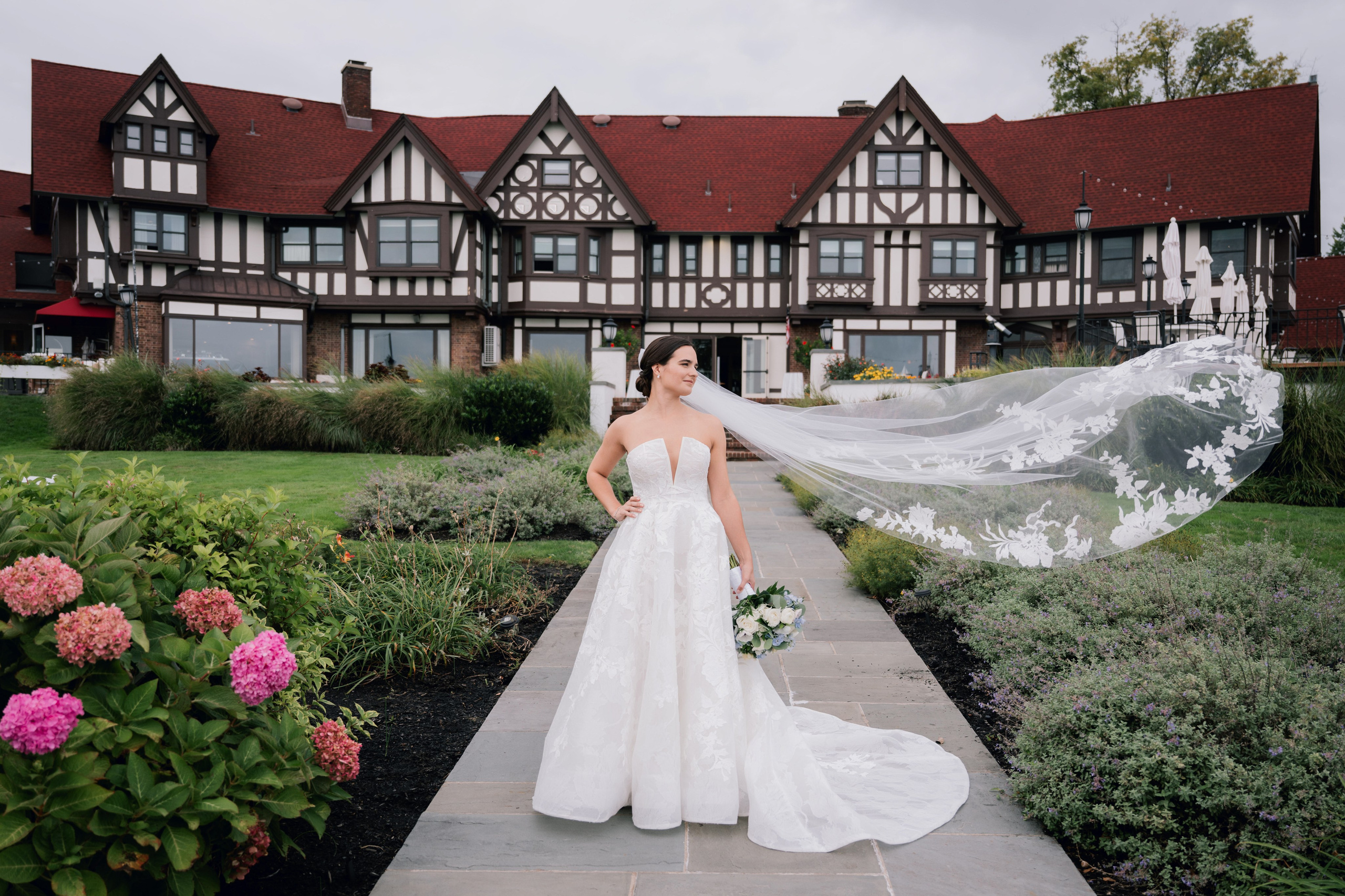 a bride standing on a walkway in front of a large house