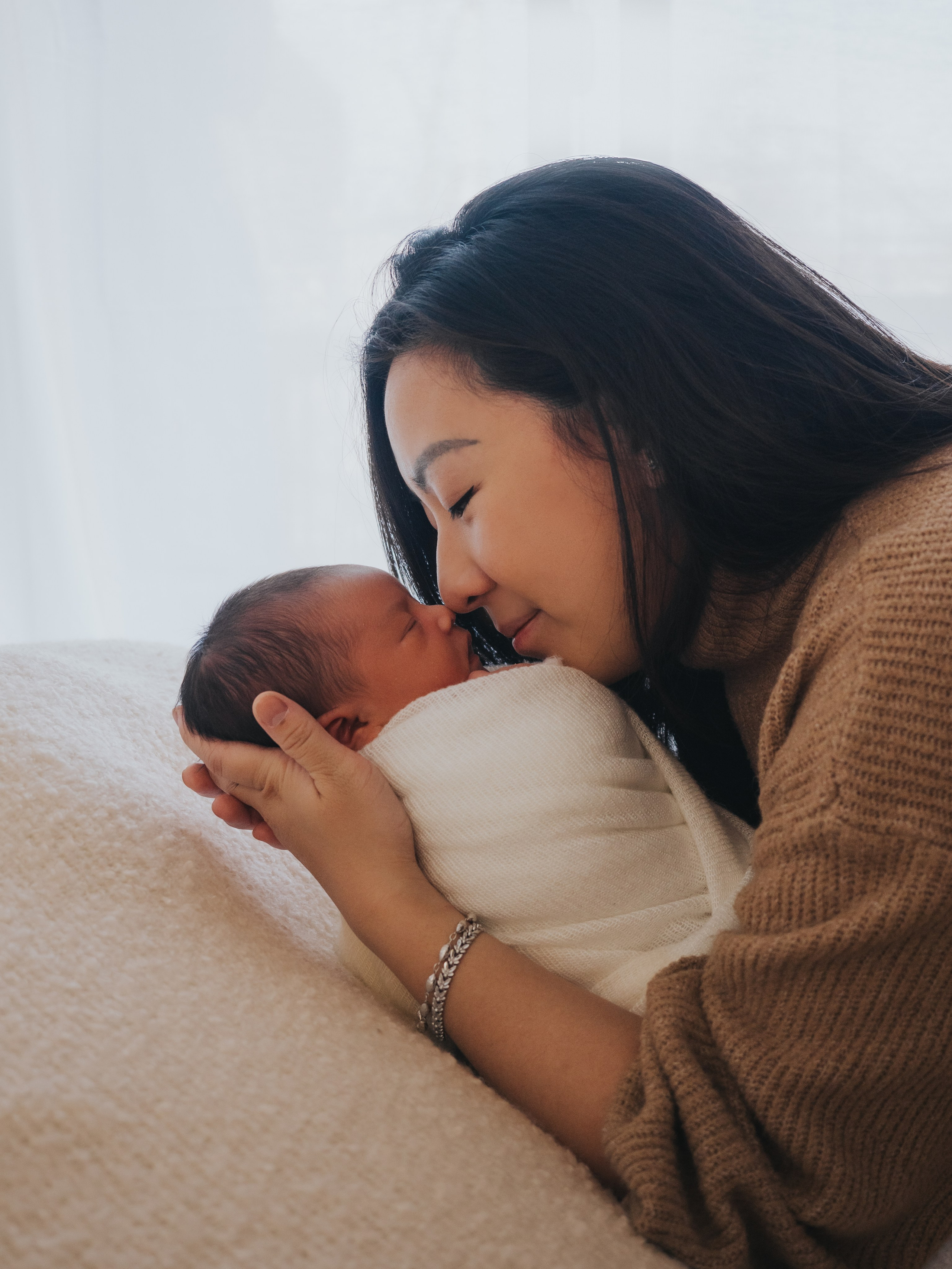 Mother and newborn exchanging nose kiss.