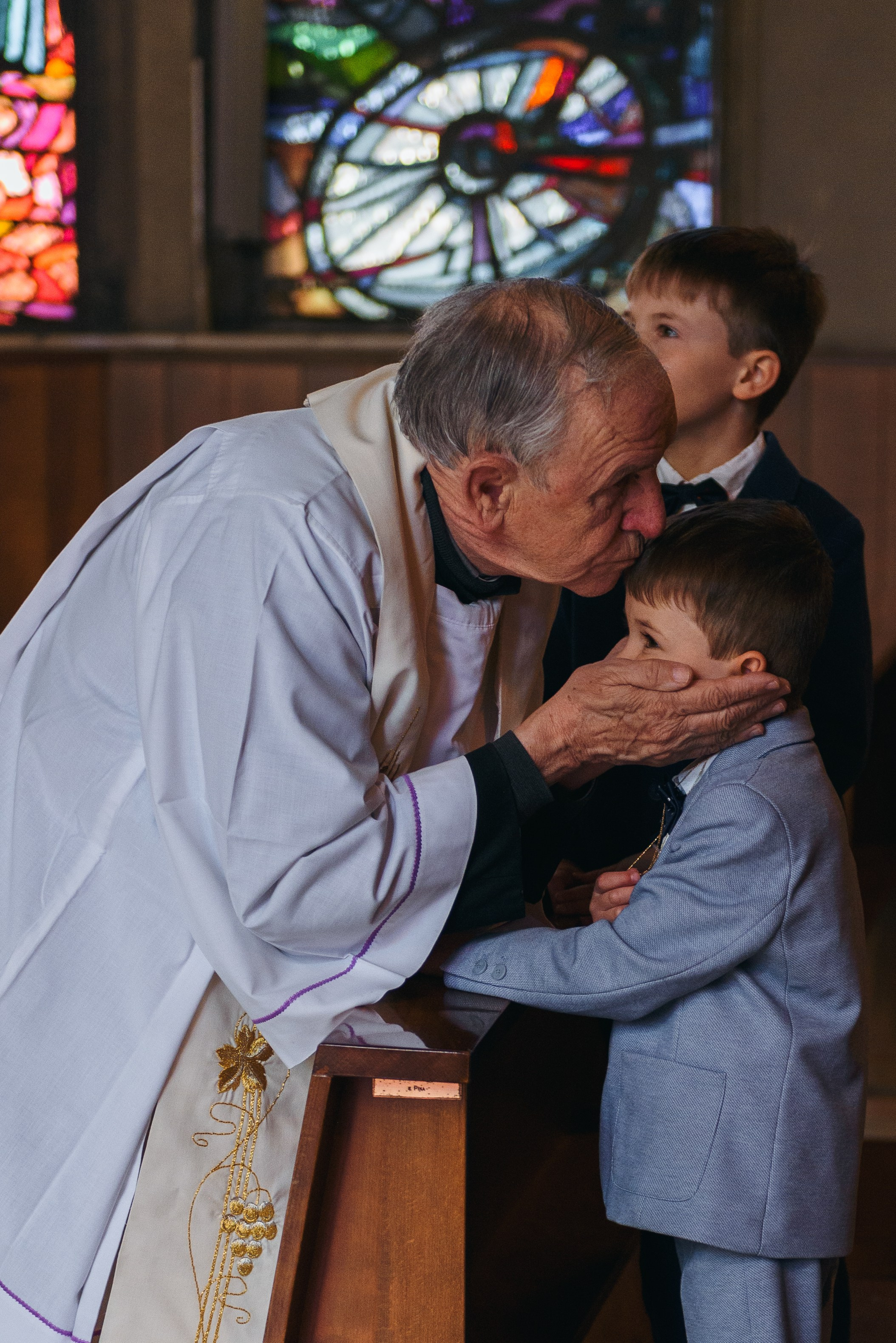 Kiss from the parish priest. Baptism. Photographer Milan baptism.
