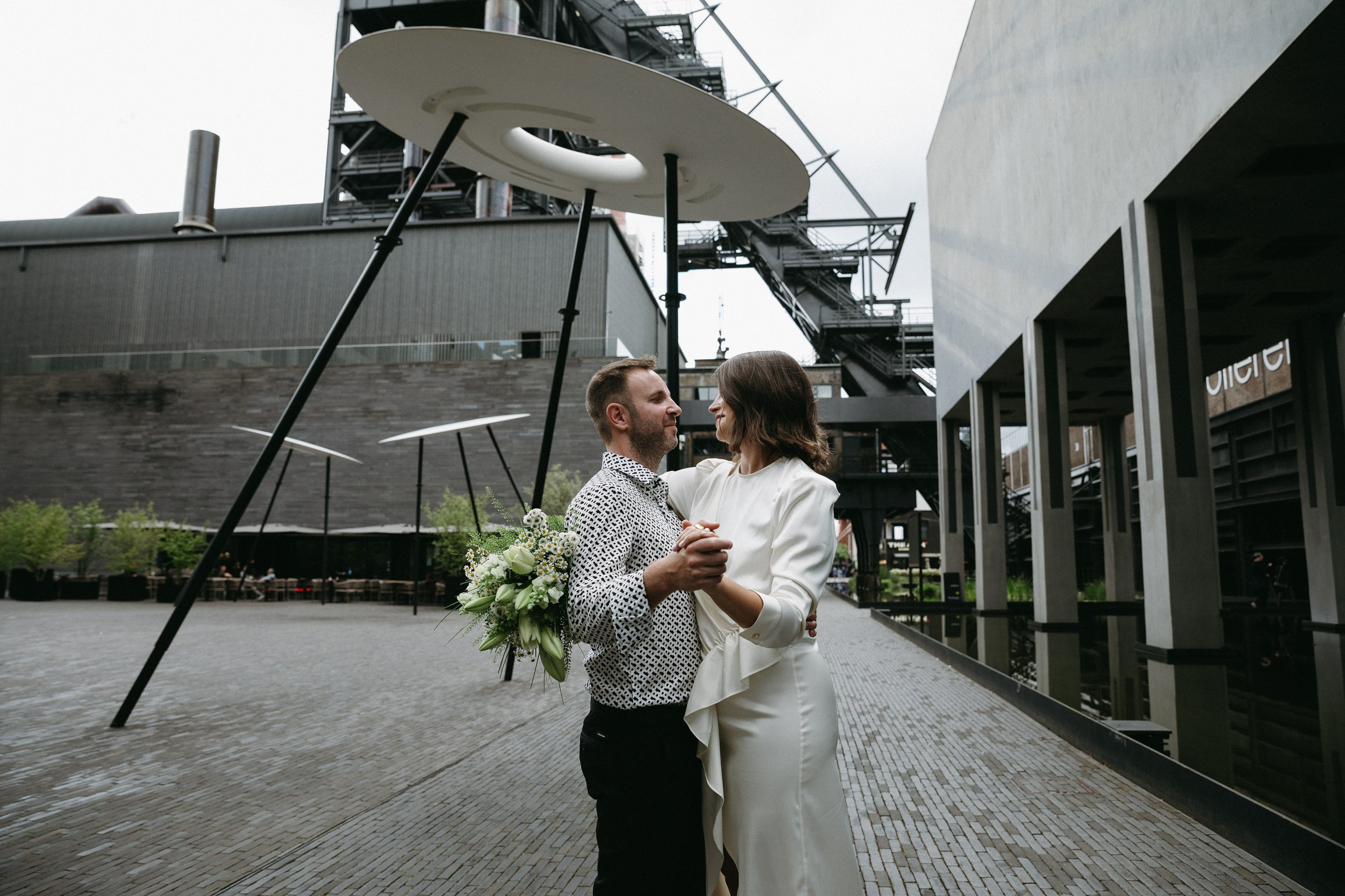 Braut und Bräutigam tanzen vor moderner Architektur am Belval Campus