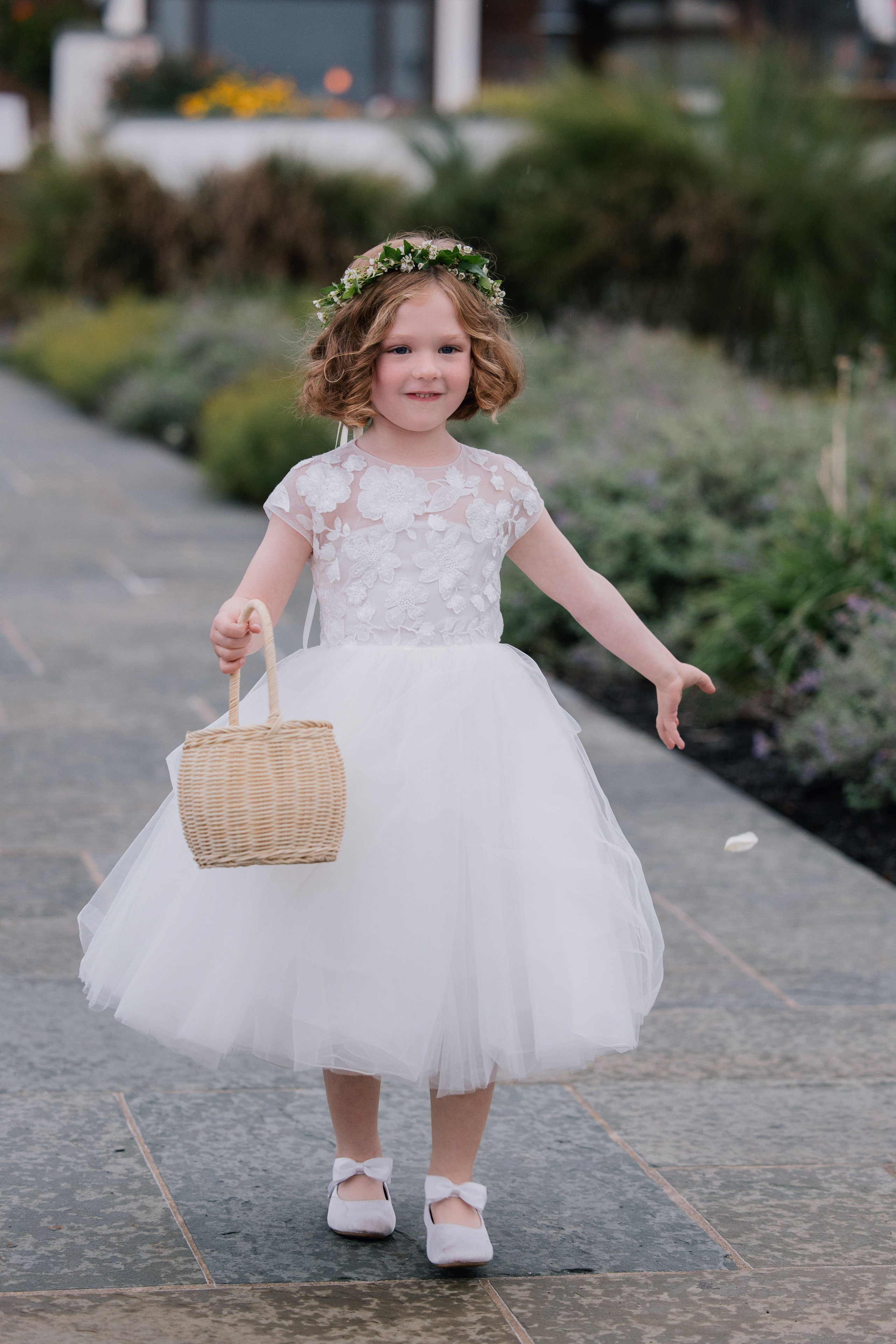 a little girl in a white dress and flower crown