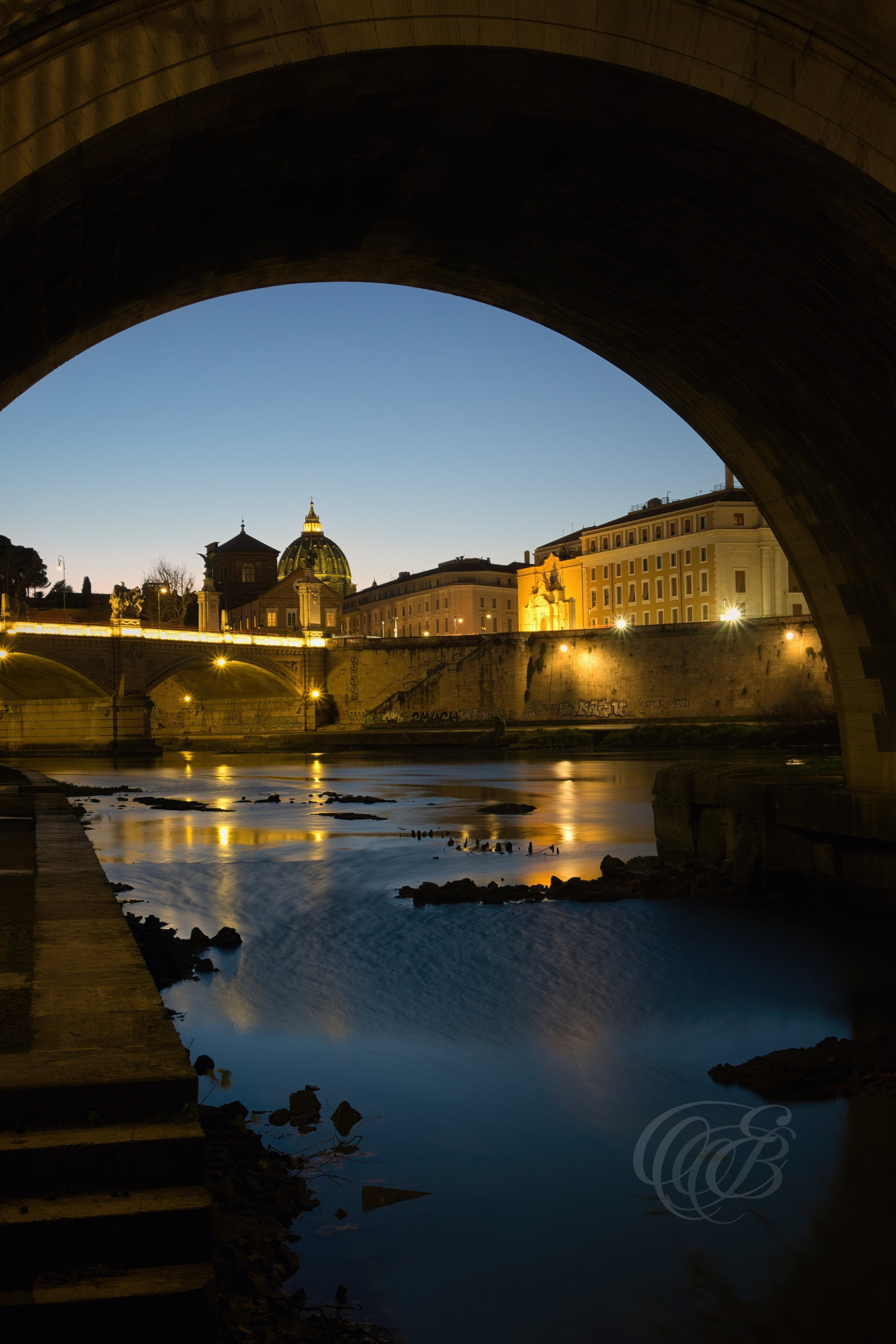 Rome, Italy – This radiant sunset photograph captures the golden light spilling beneath the arches of the Ponte Sant’Angelo. The warm reflections on the Tiber River and the soft glow of the setting sun create a tranquil, almost ethereal atmosphere in the heart of Rome. A luminous piece that celebrates the poetry of light and architecture. Eduardo Bartoli Photography.