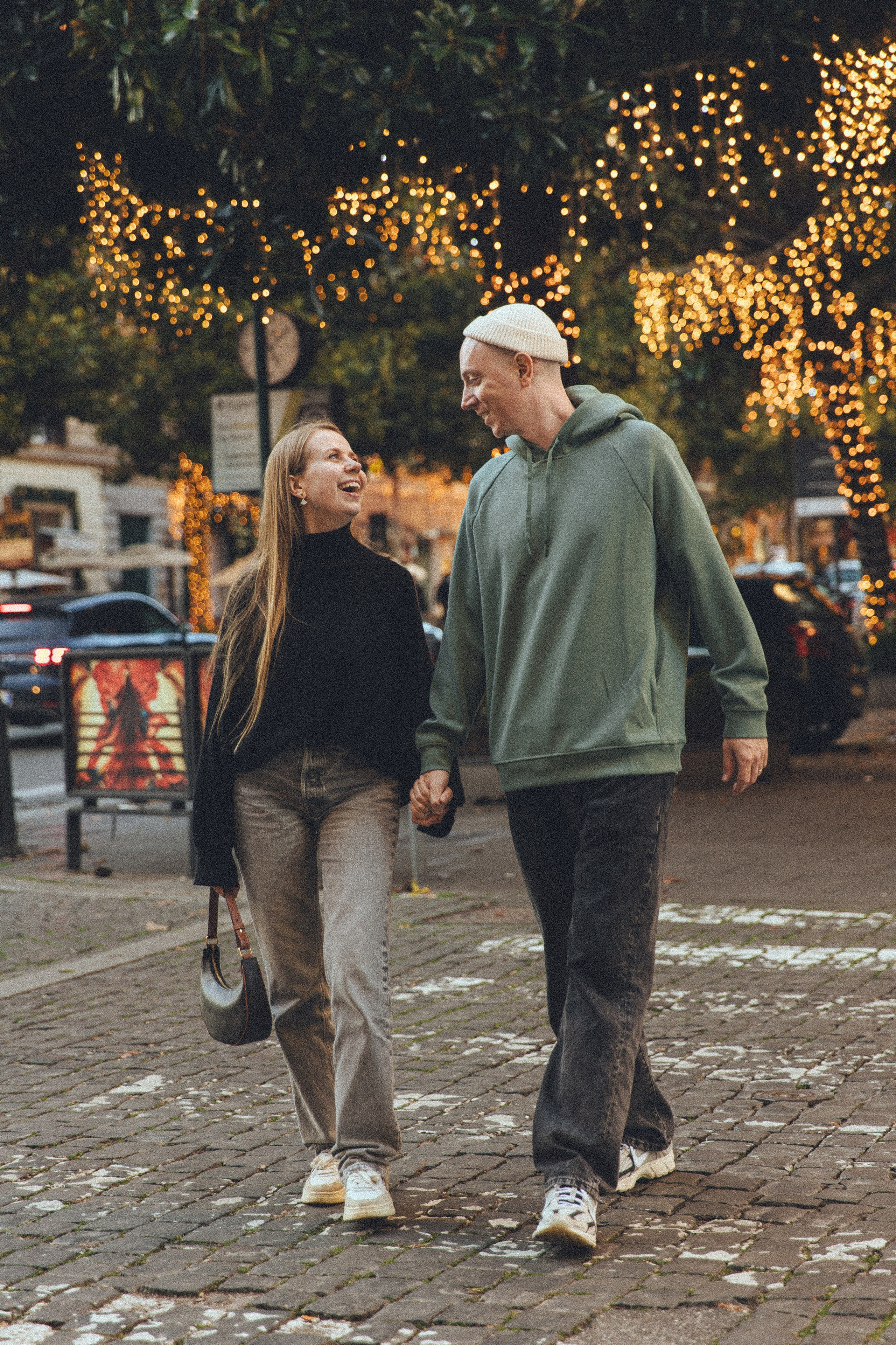 A candid photograph of a couple embracing on a cobblestone street in Rome, their expressions full of joy.