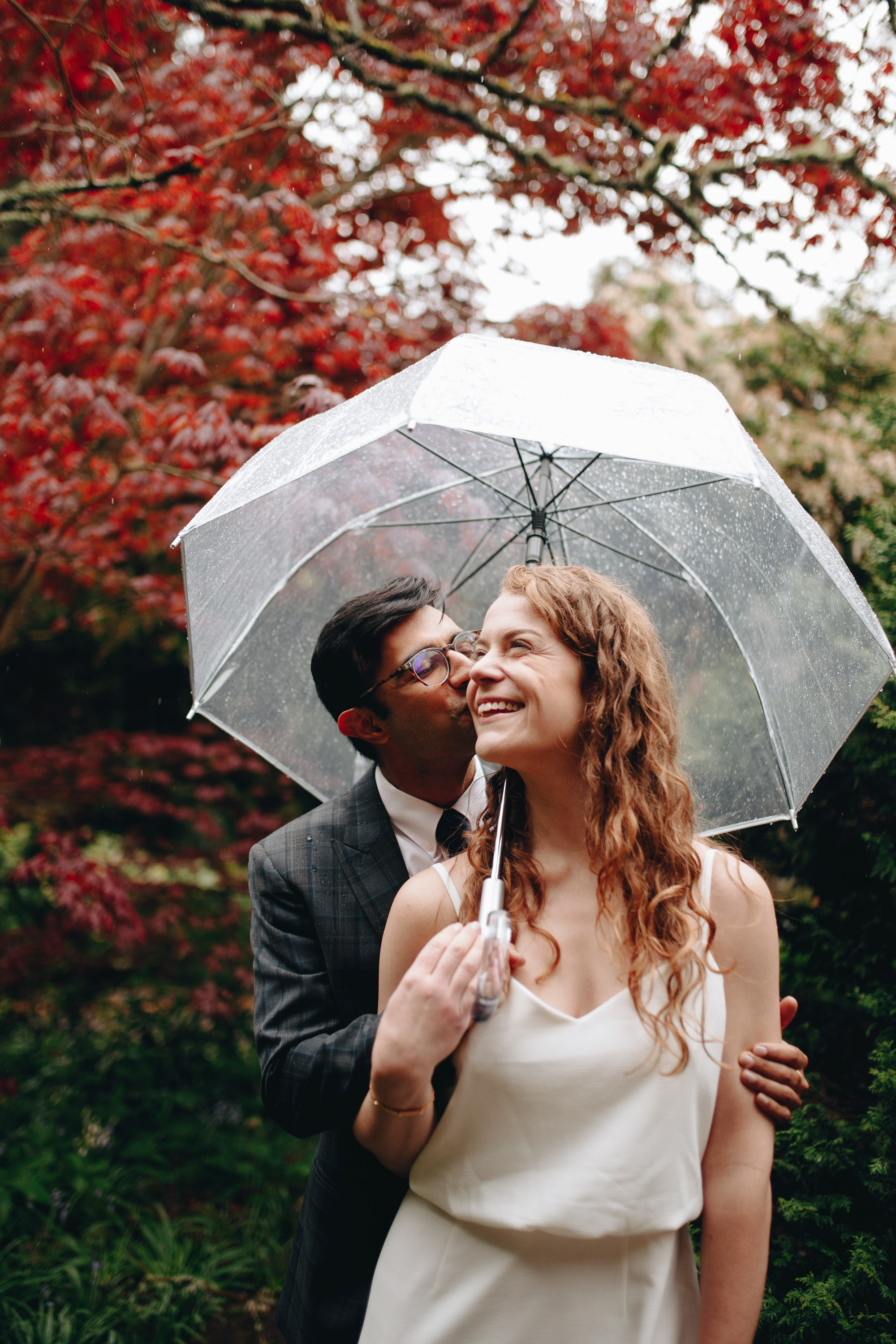 Bride under umbrella with autumn leaves, romantic moment