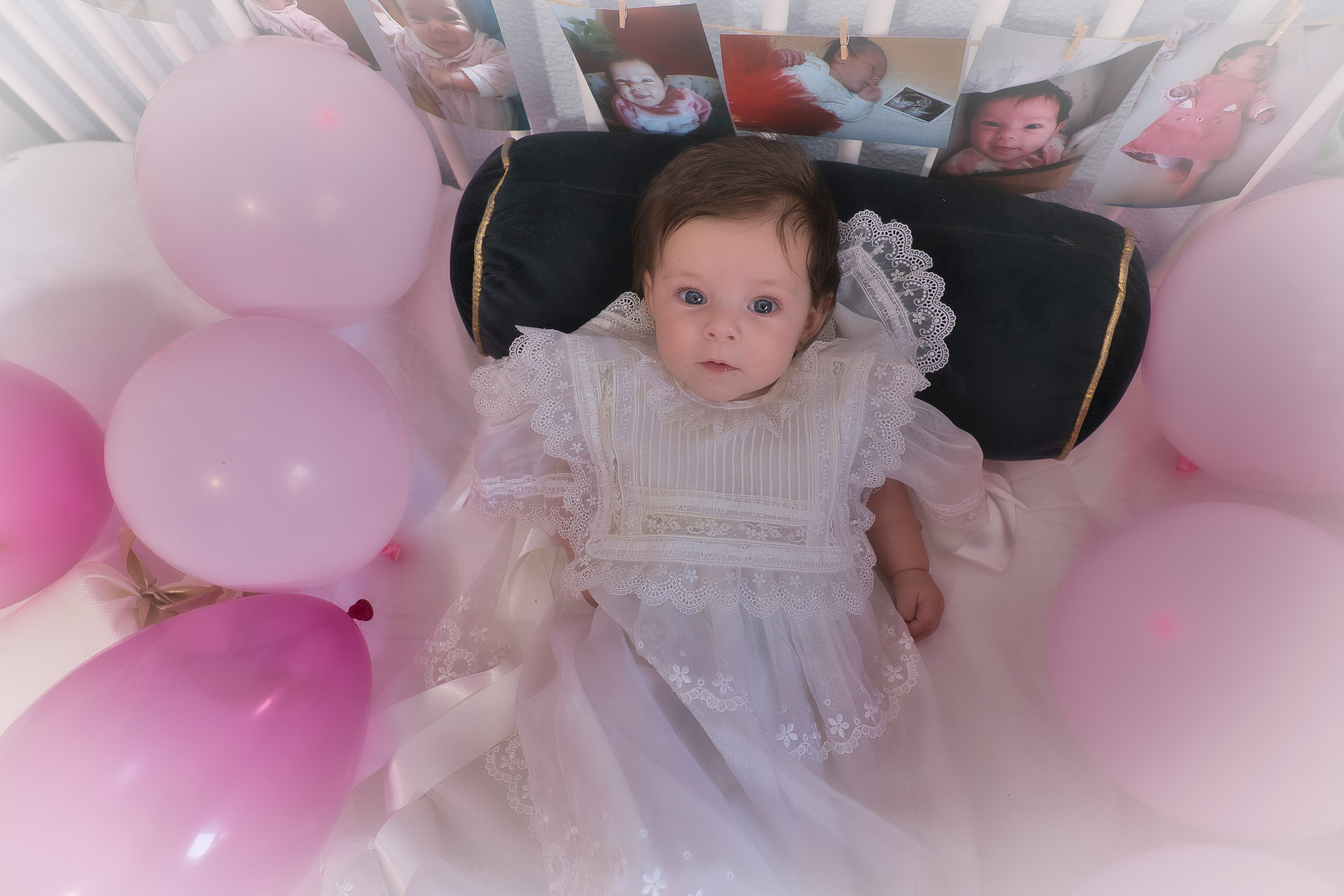 Niña vestida con traje de bautizo blanco, sostenida por sus padres en la iglesia.
