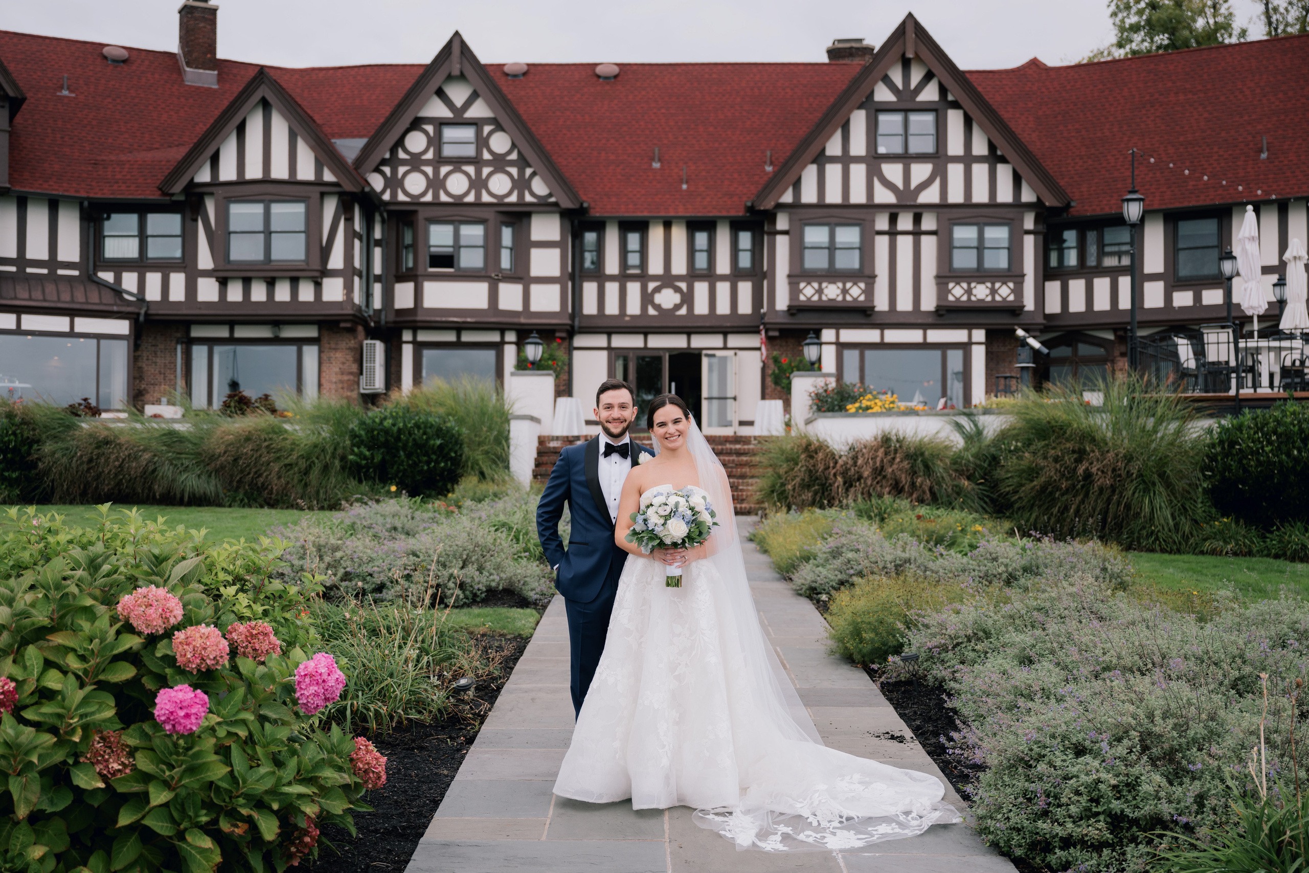 a bride and groom walking in front of a large house