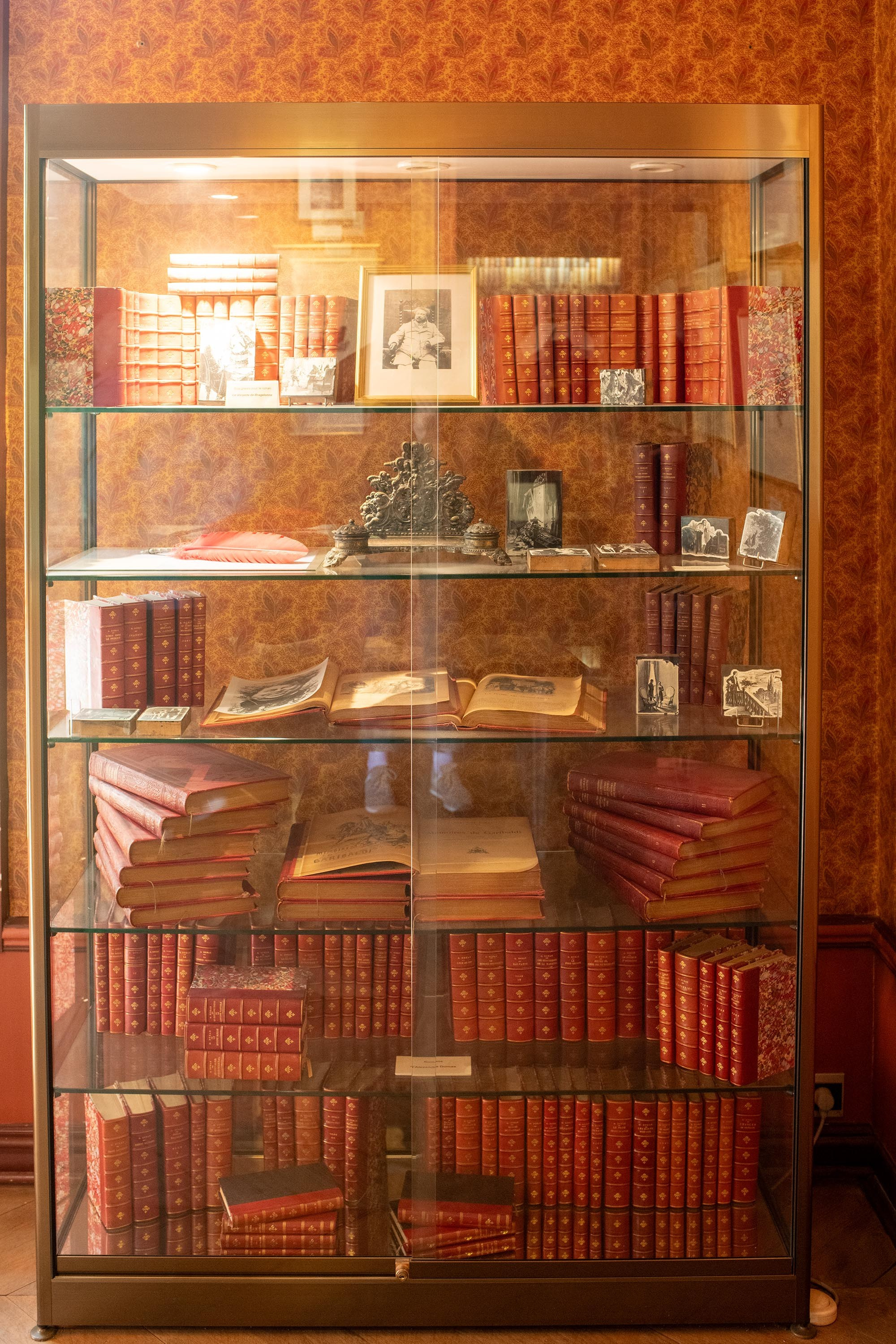 Display case with rare books, illustrated editions, and Alexandre Dumas memorabilia at Château de Monte-Cristo near Paris