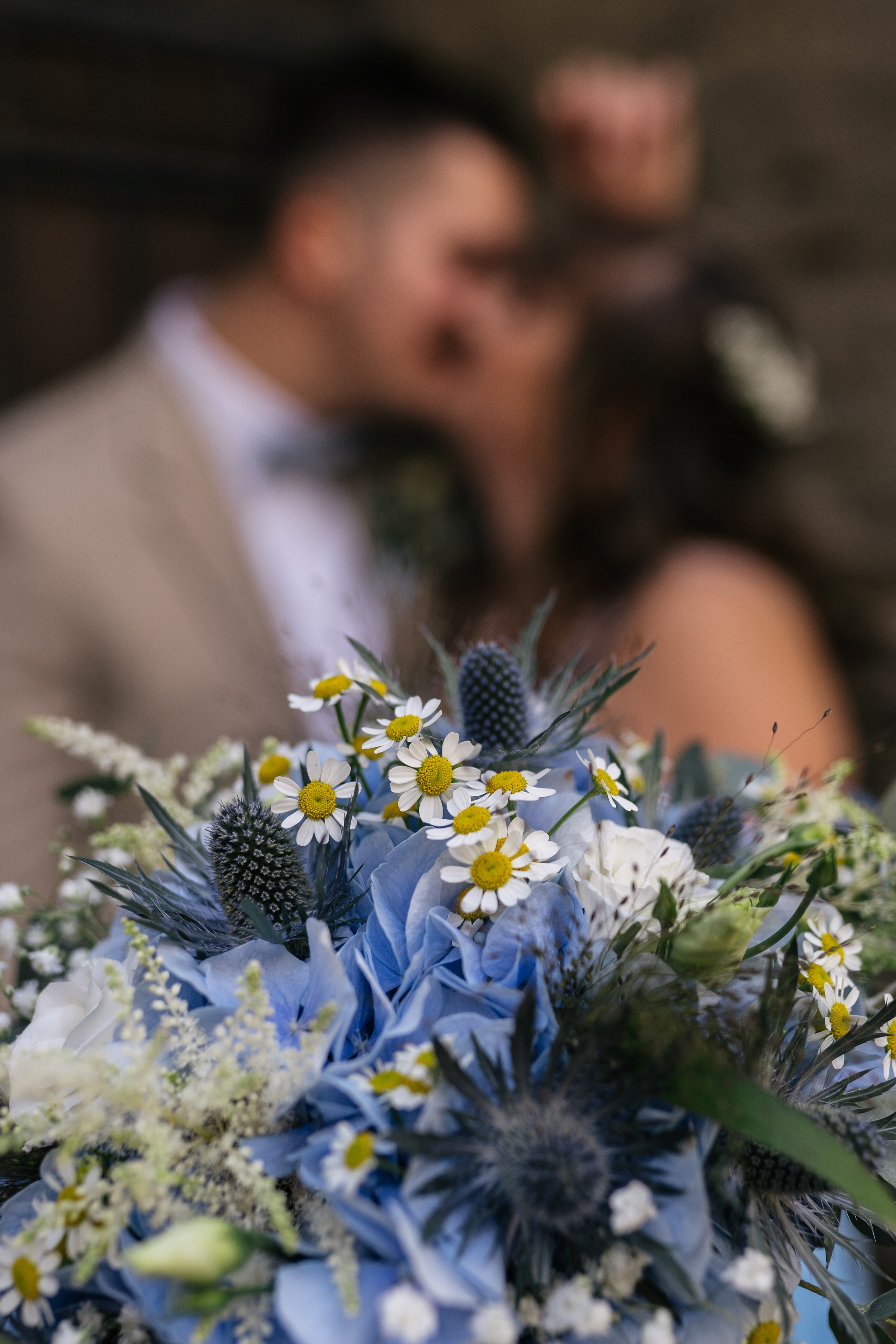 Der Brautkuss im Hintergrund wird von einem prachtvollen Blumenstrauß im Vordergrund begleitet