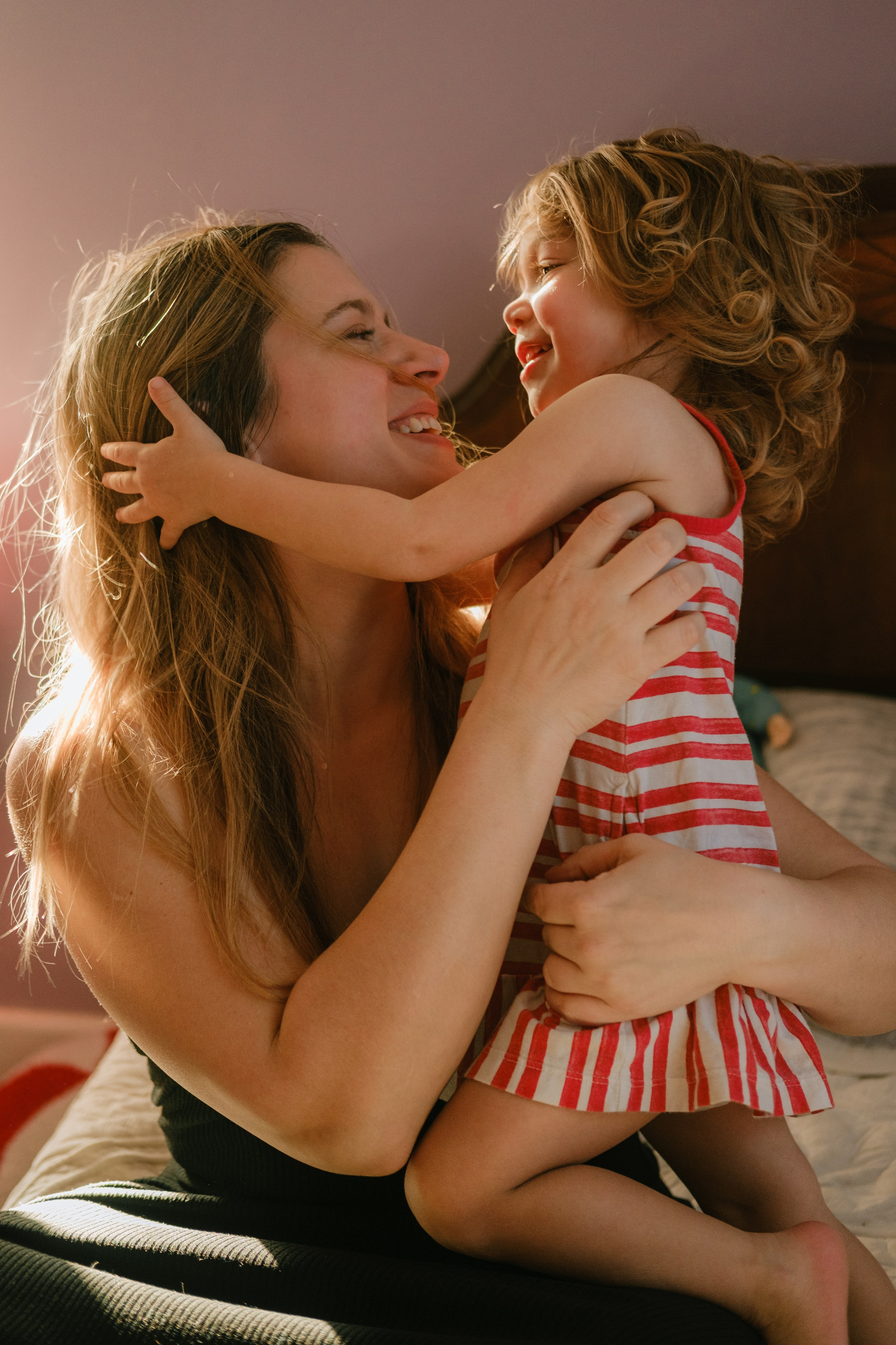 A mother laughing as she catches her toddler mid-stride in their Richmond living room, capturing the unscripted energy of parenthood.