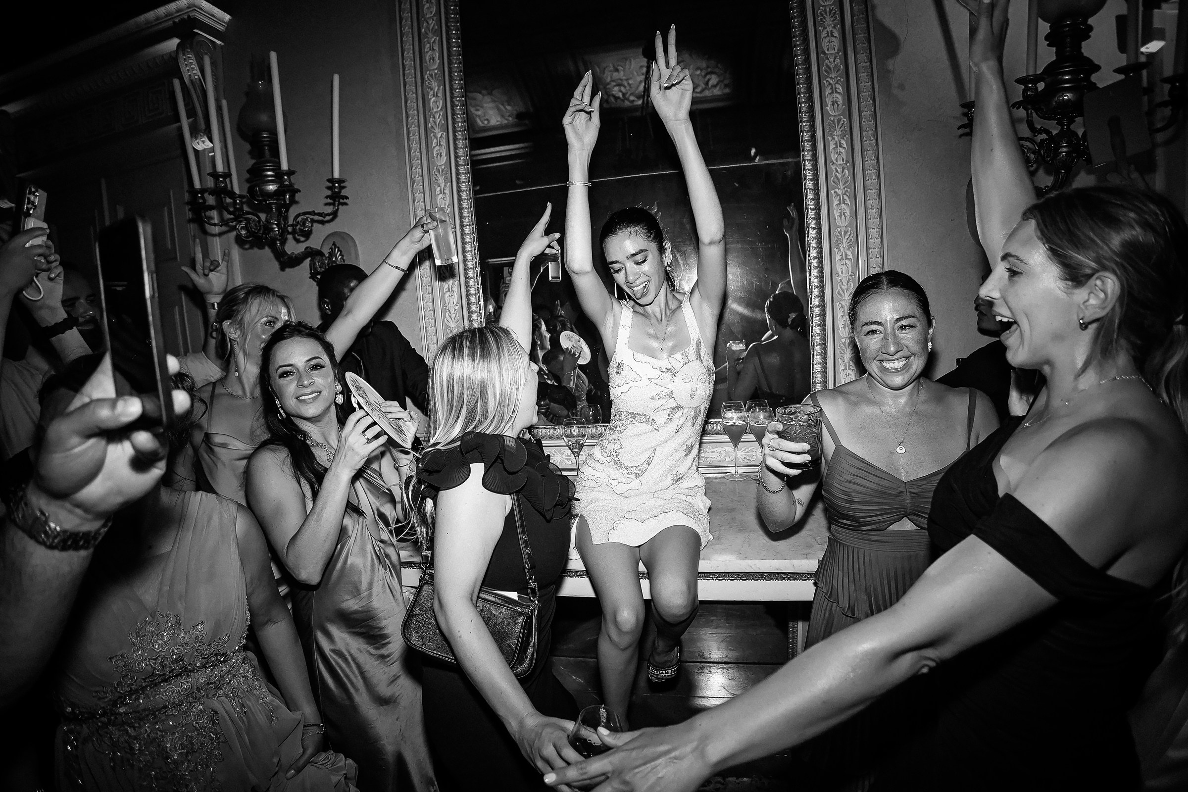 Bride dancing with friends, hands raised high, immersed in the joyous celebration.