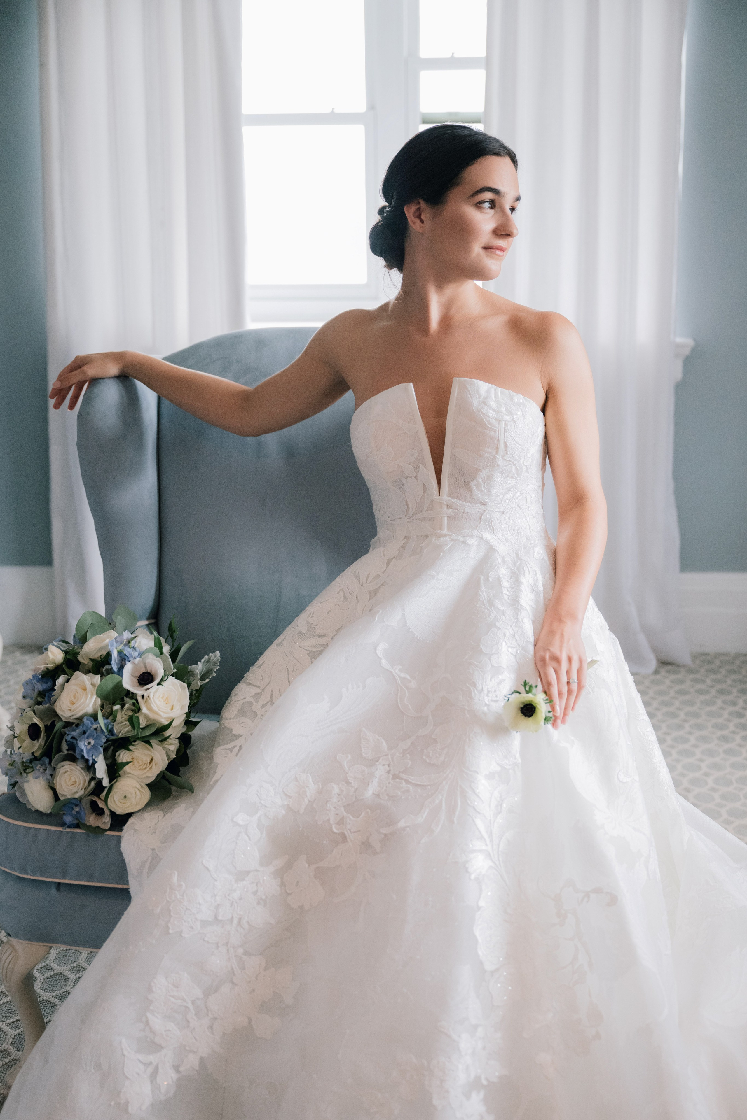 a bride sitting on a blue couch in her wedding dress