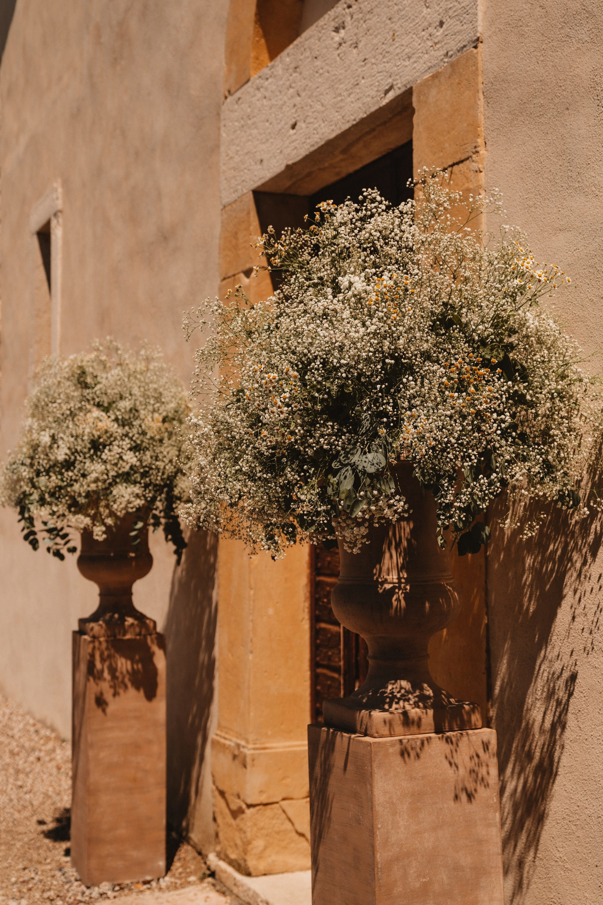Entrada rústica de quinta com arranjos florais exuberantes em vasos de pedra, en Verona, Itália.
