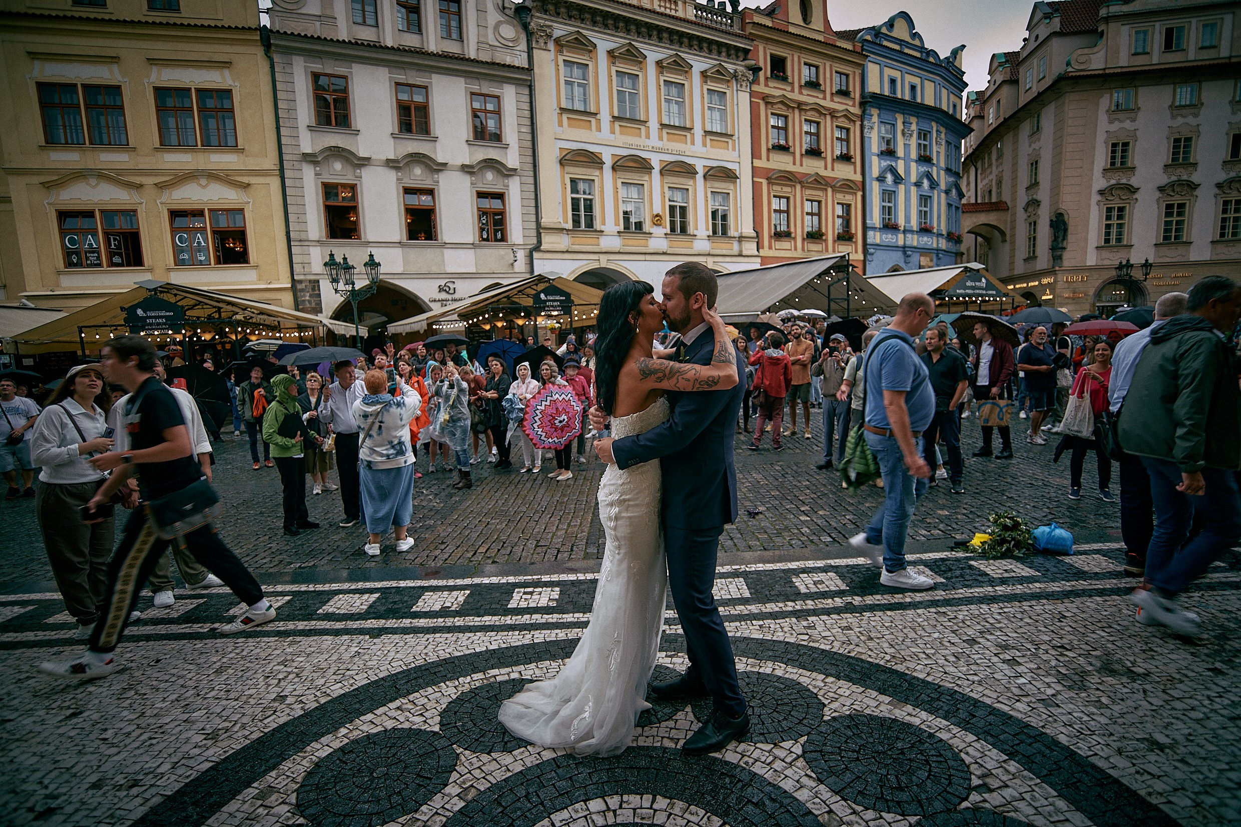 Couple embracing affectionately with crowds watching Astronomical Clock.