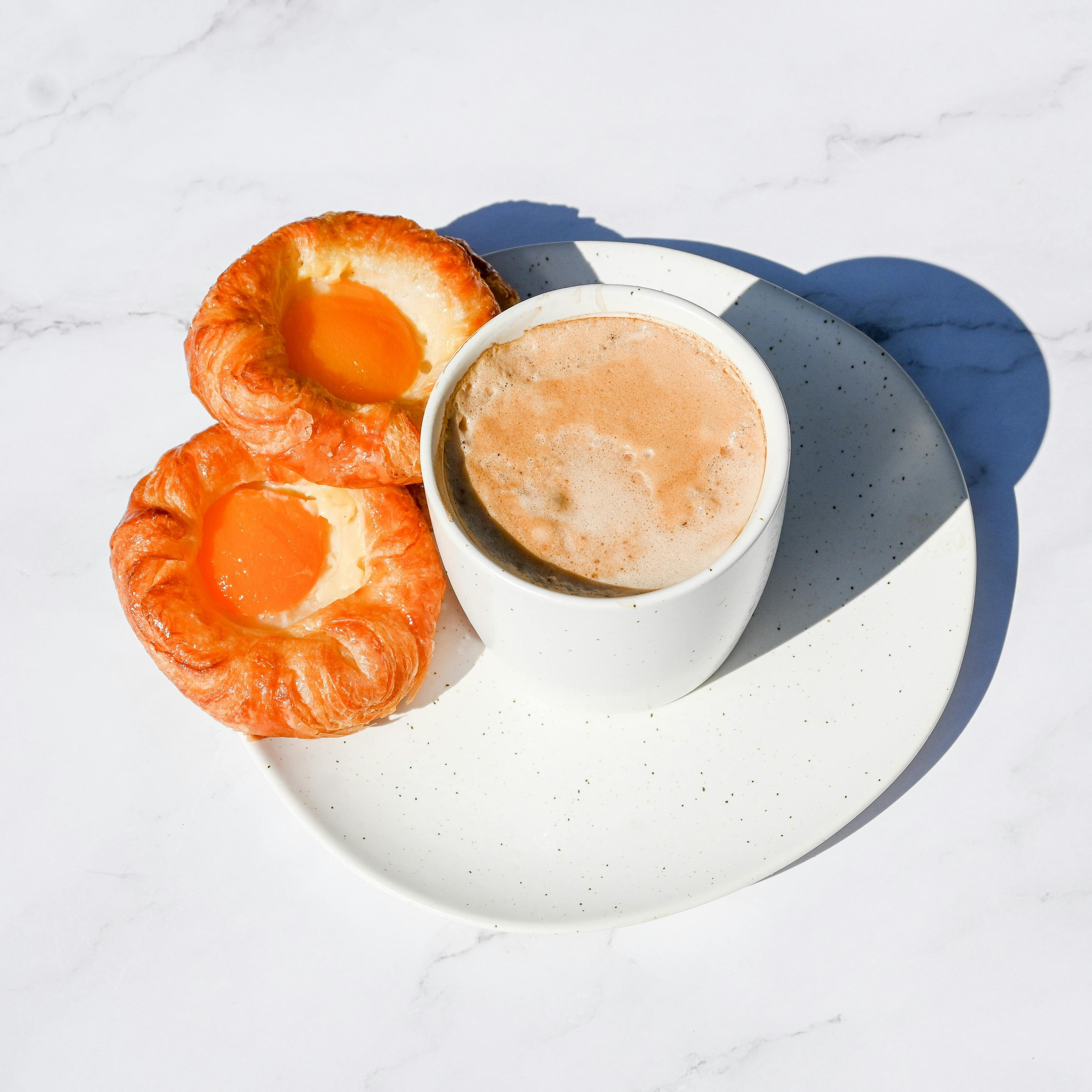 Minimal food photography of coffee and croissant on marble table, photographed by London food photographer Jay Soundo