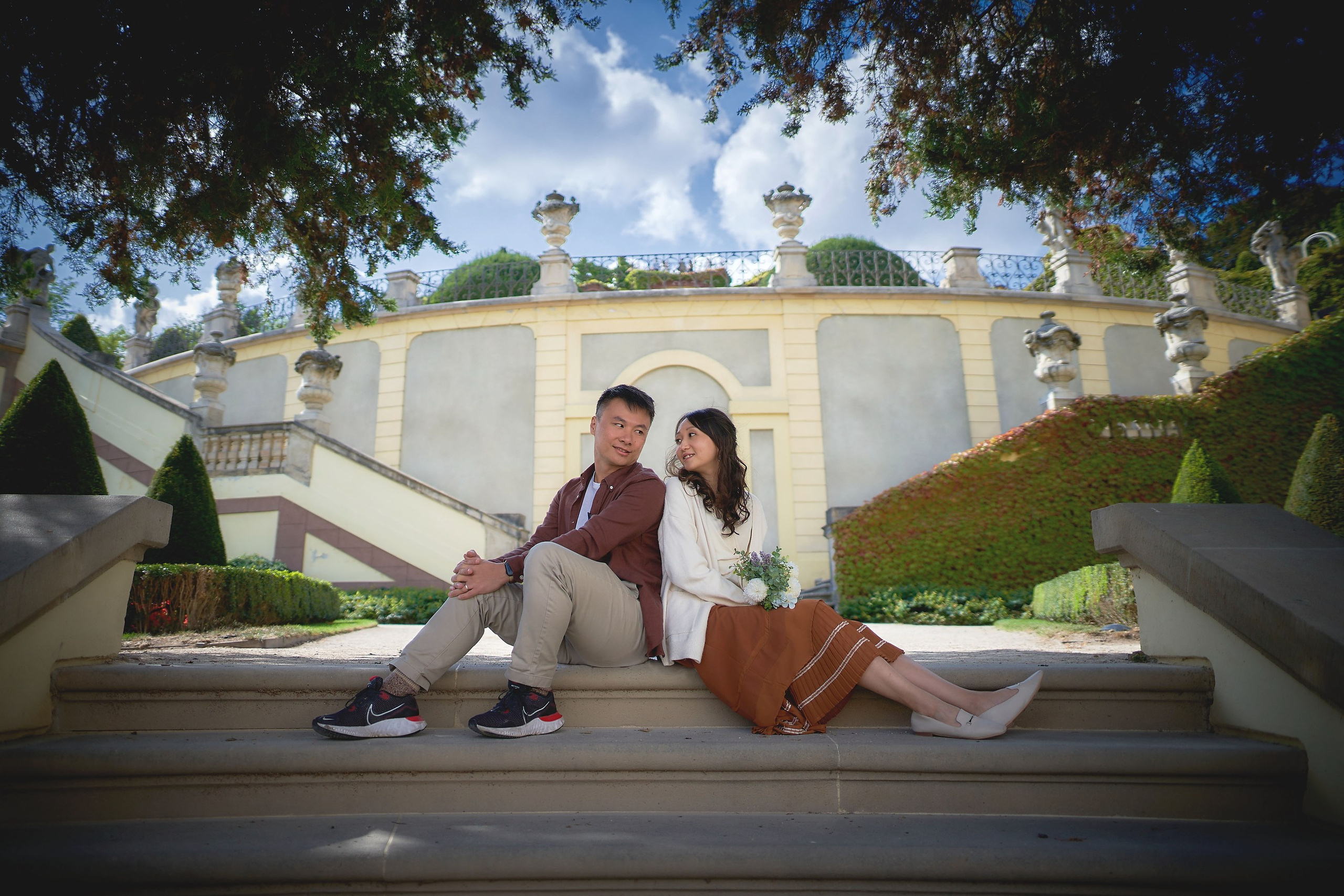 Newlyweds Eva and Conan sitting alone on stairs in Vrtba Garden, Prague.