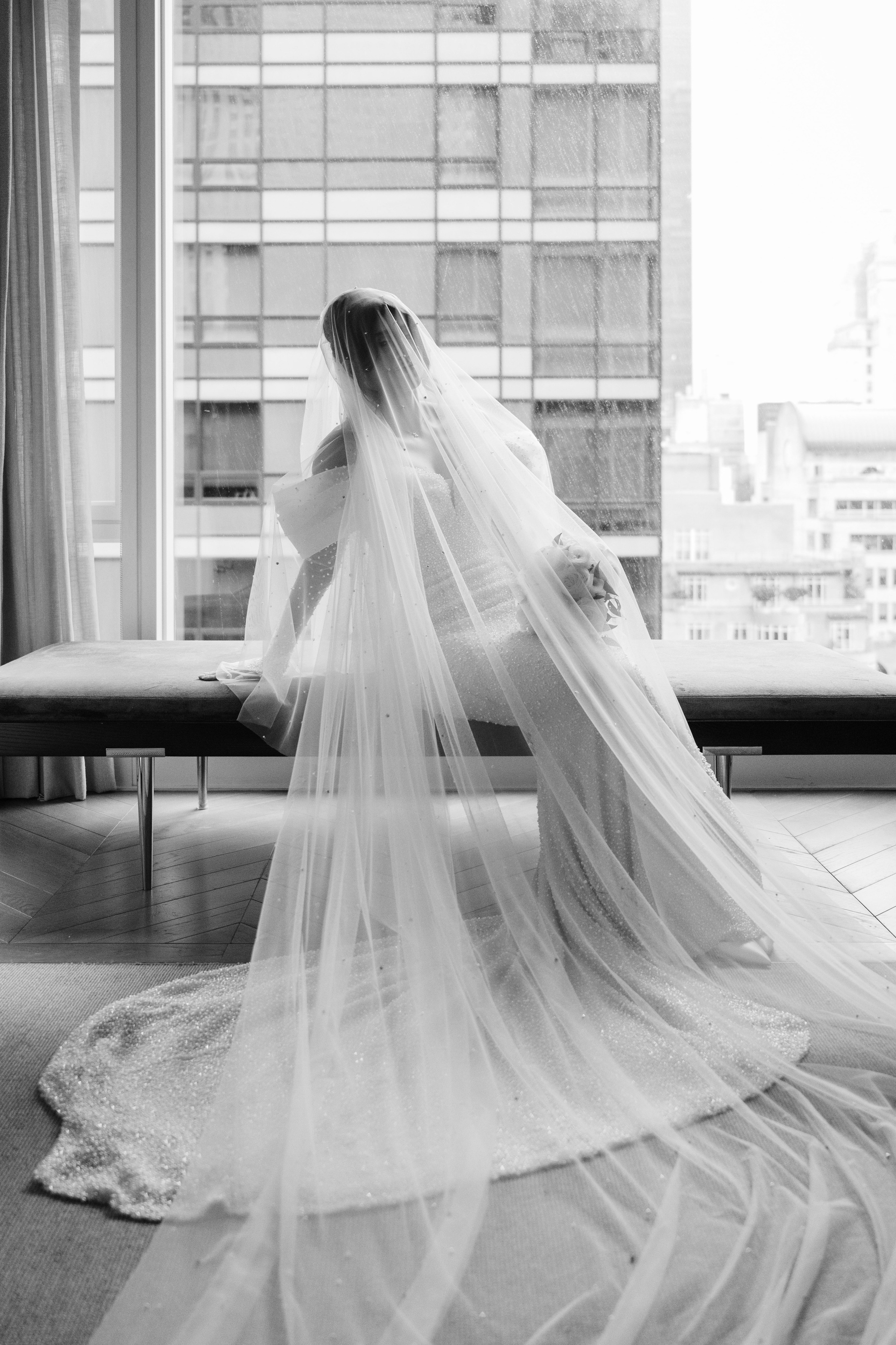 a bride sitting on a bench in front of a window