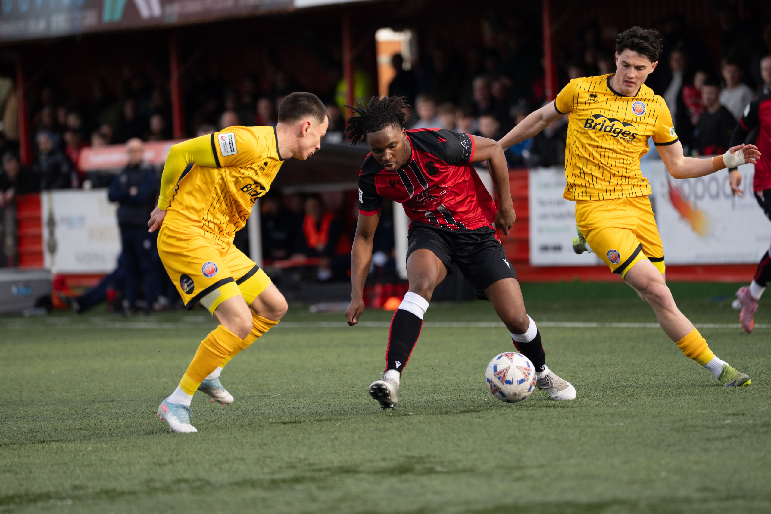 Tamworth, England — February 14, 2026: Daniel Isichei of Tamworth FC controls the ball under pressure from Aldershot Town players during the Enterprise National League match between Tamworth FC and Aldershot Town at The Lamb Ground. Photo: Jay Soundo