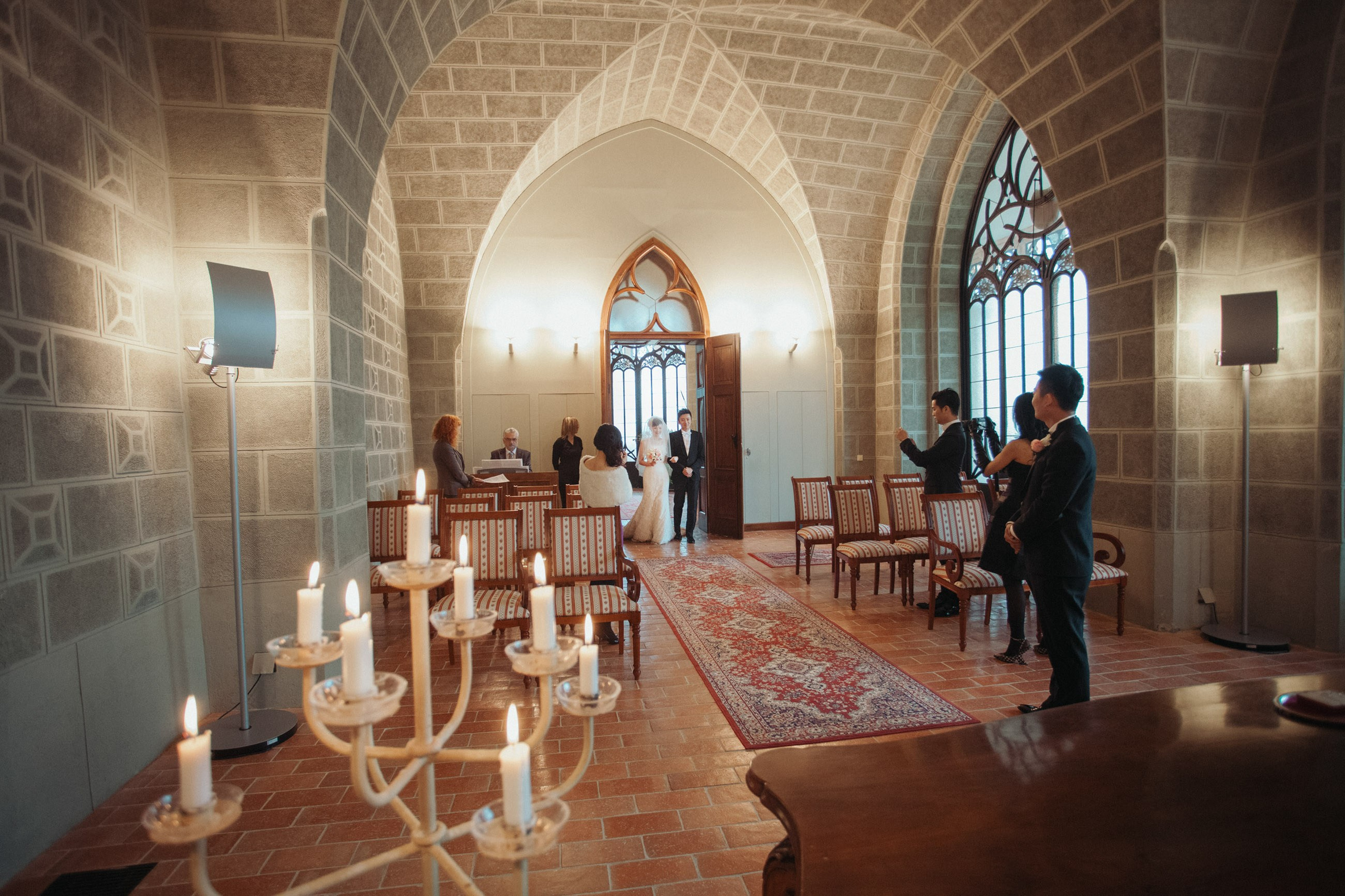 A bride is escorted into a candlelit ceremonial hall at the Castle Hluboka.