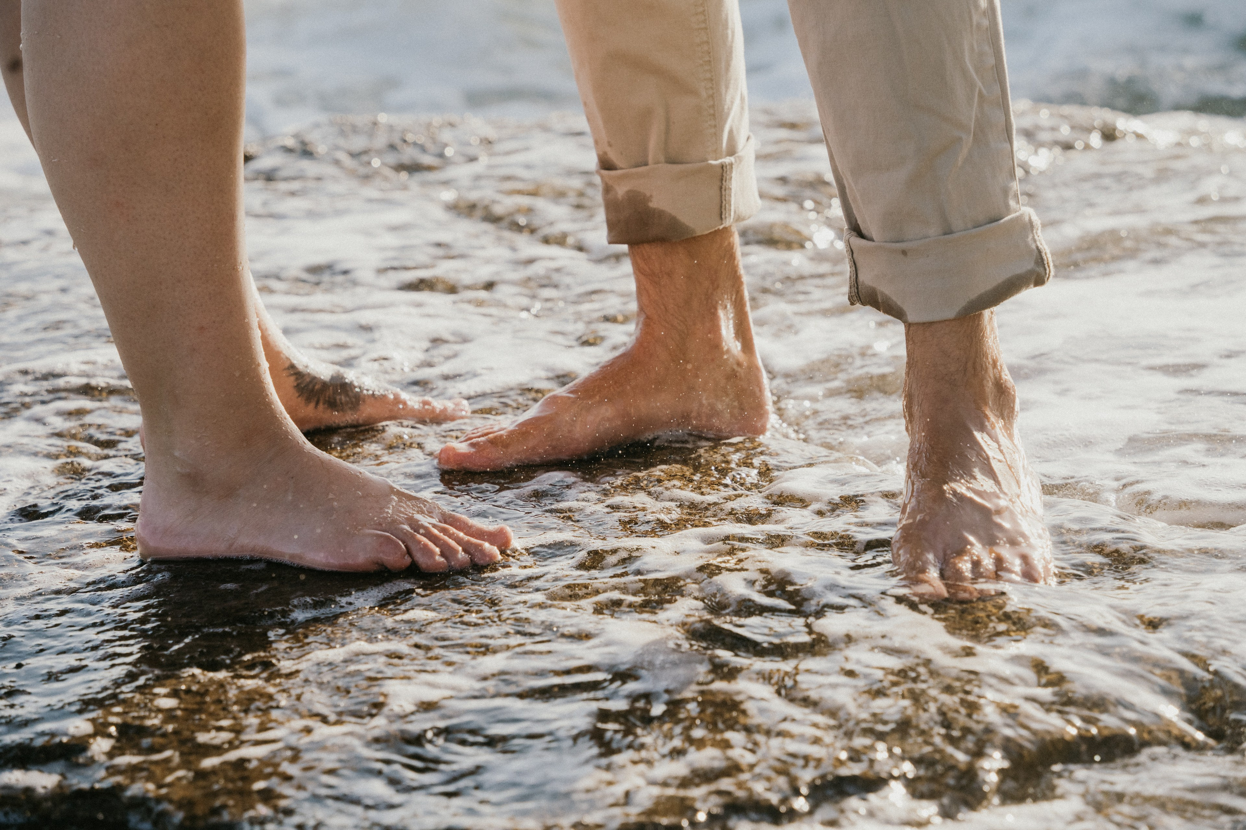 Intimní elopement focení páru u moře, detail bosých nohou ve vodě, přirozený a autentický svatební okamžik.