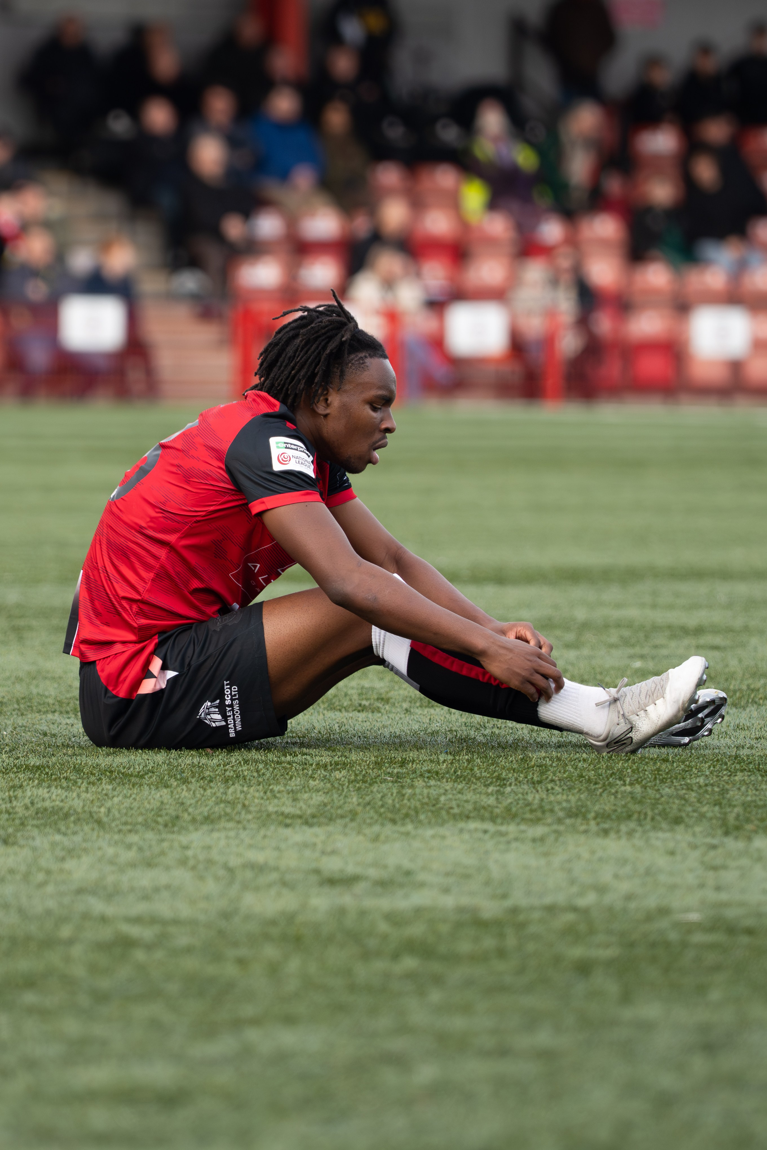 Tamworth, England — February 14, 2026: Tamworth’s Daniel Isichei adjusts his boot during the Enterprise National League match between Tamworth and Aldershot Town at The Lamb Ground. Photo: Jay Soundo
