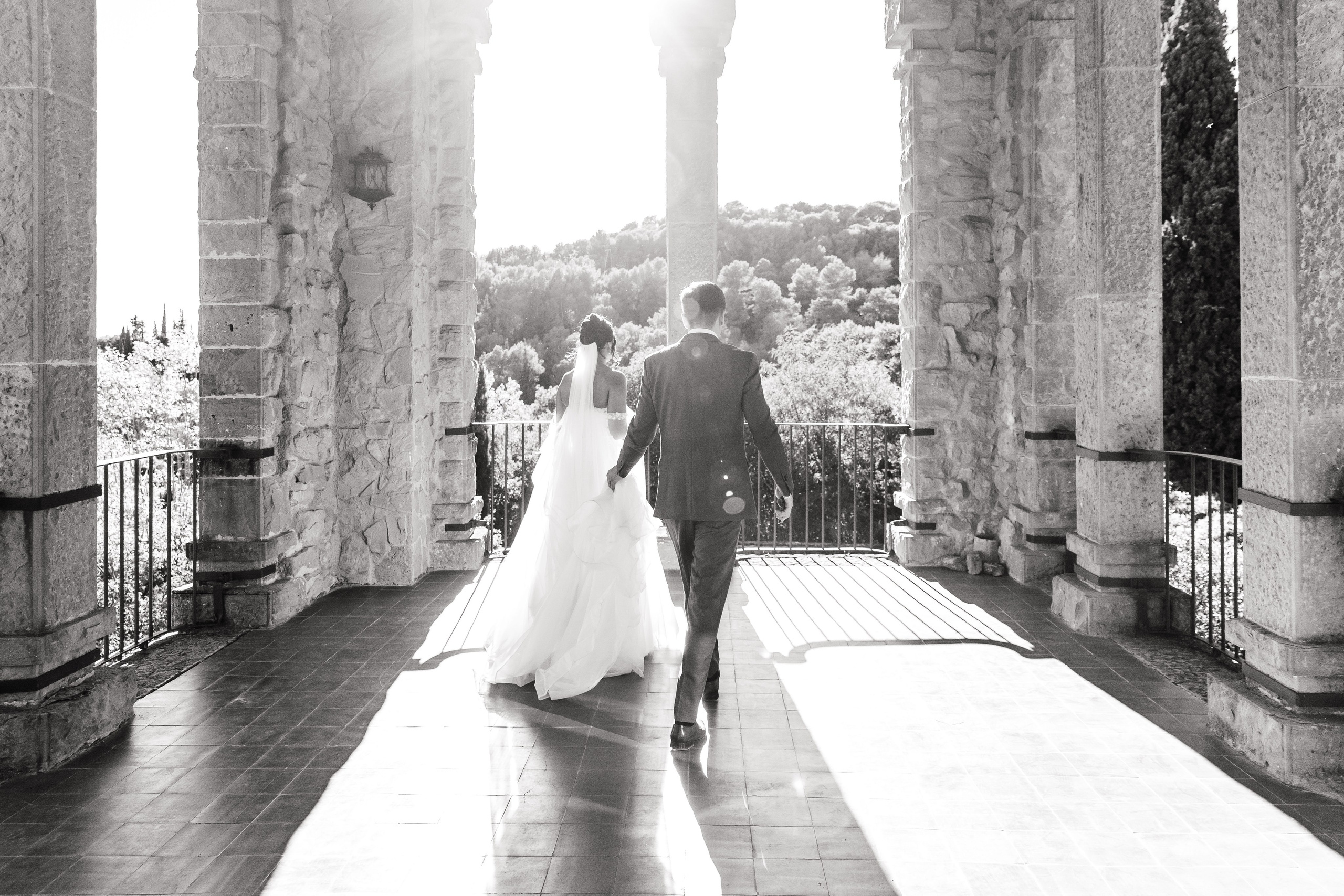 The bride and groom are walking hand in hand through the wedding venue in Barcelona.