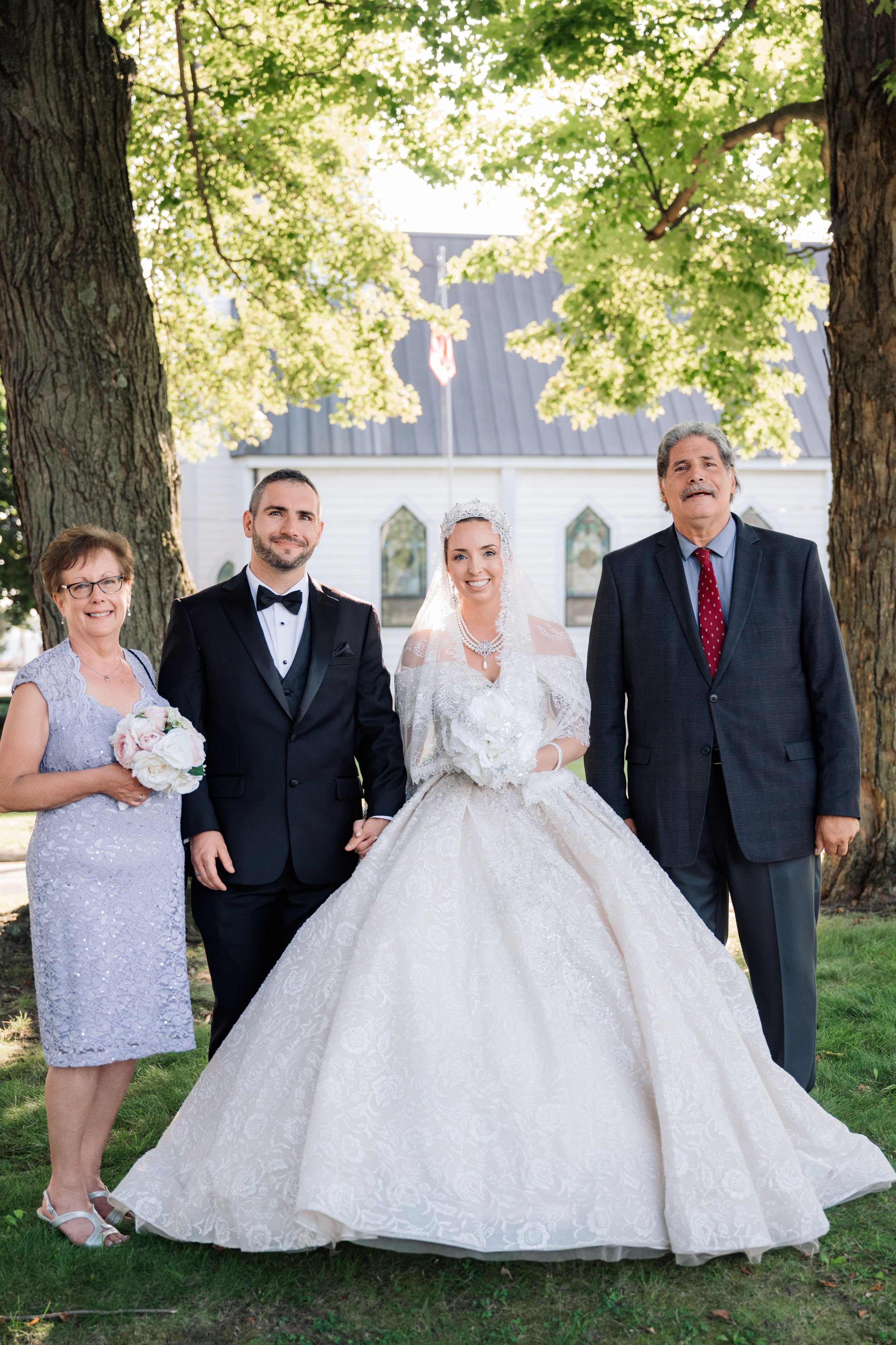 a bride and groom pose for a photo with their family