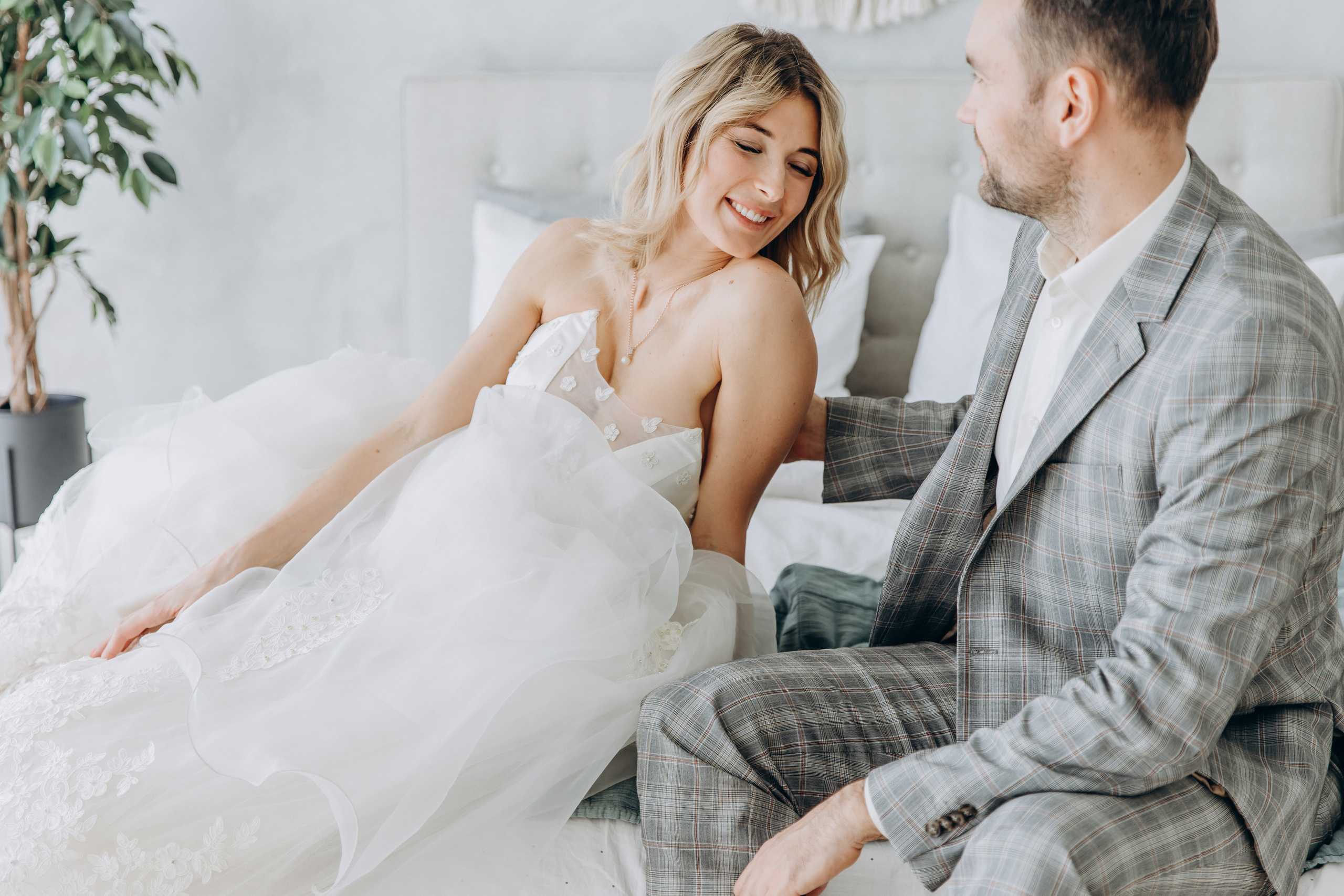 The bride on the bed looks at the groom, a beautiful photo