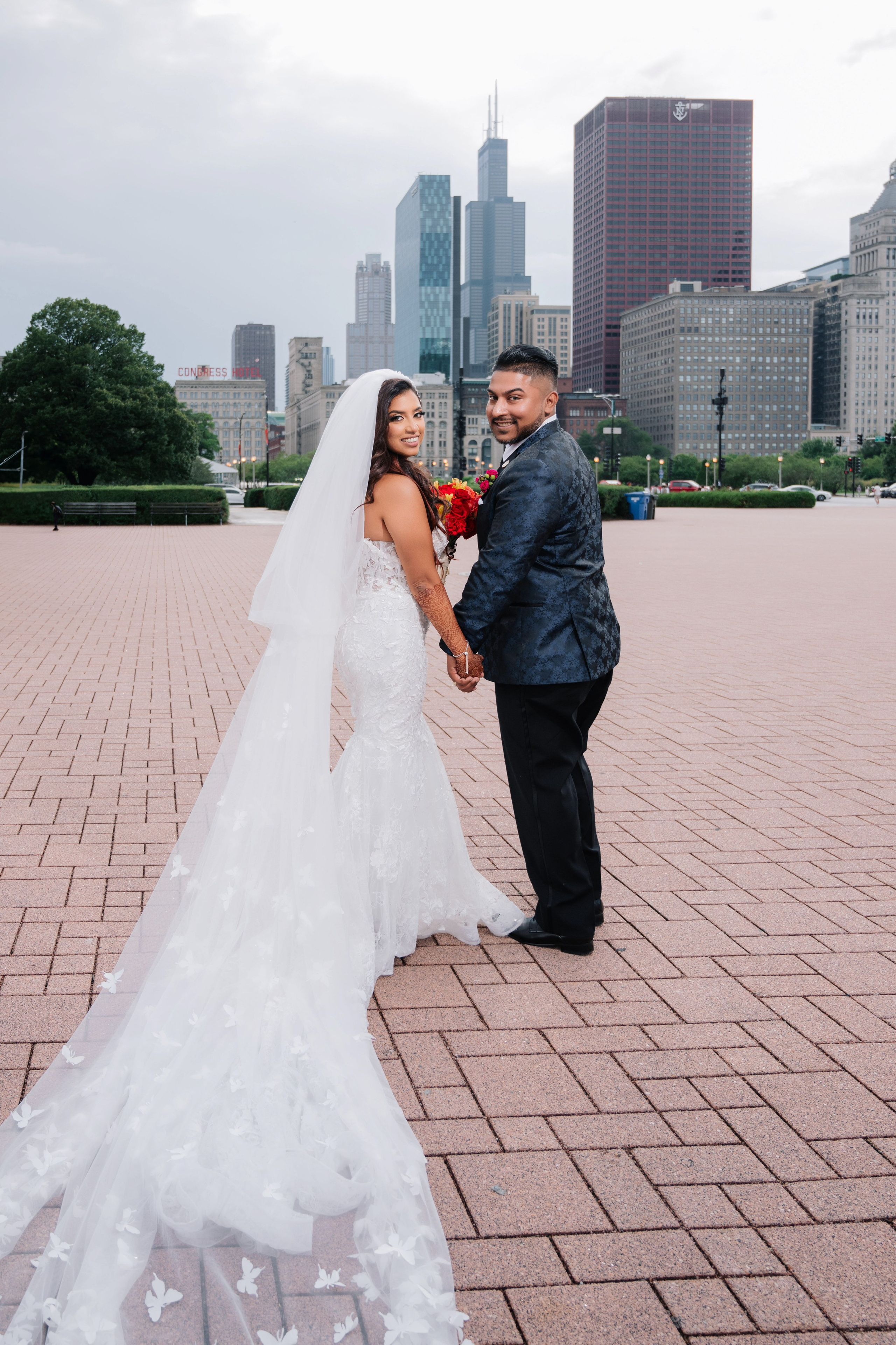 a bride and groom pose for a photo in front of the city skyline