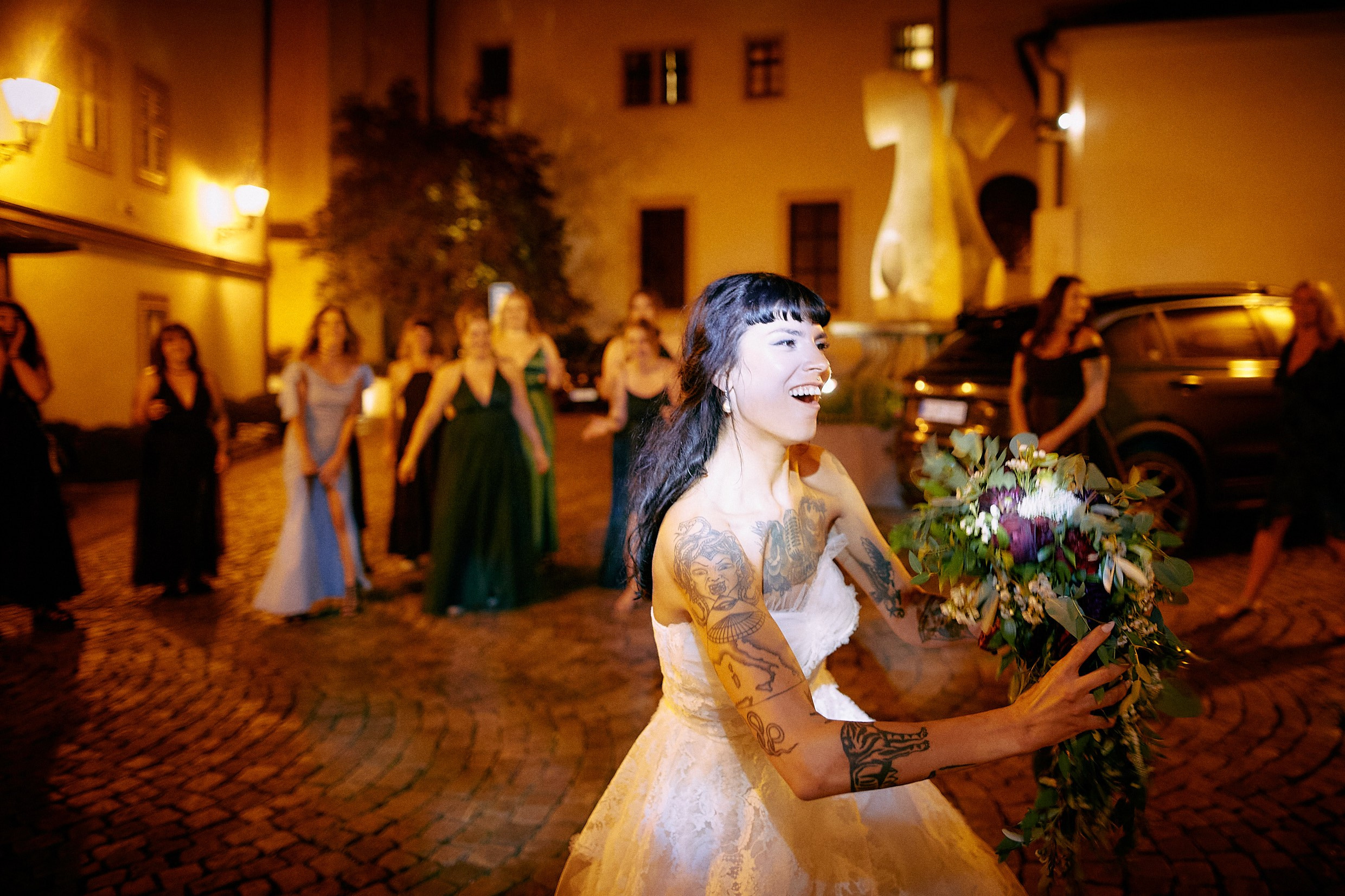 Female guests laughing in anticipation during bouquet toss moment.